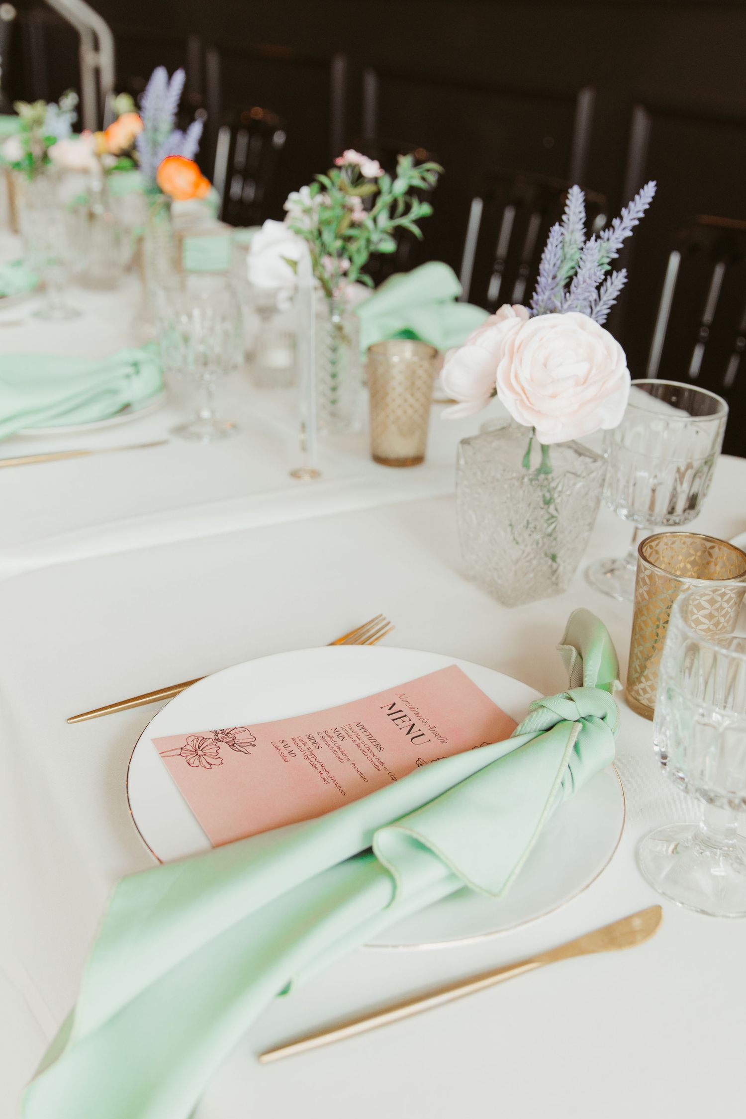 Wedding place settings with mint green napkins and blush pink menu cards on white tablecloths.