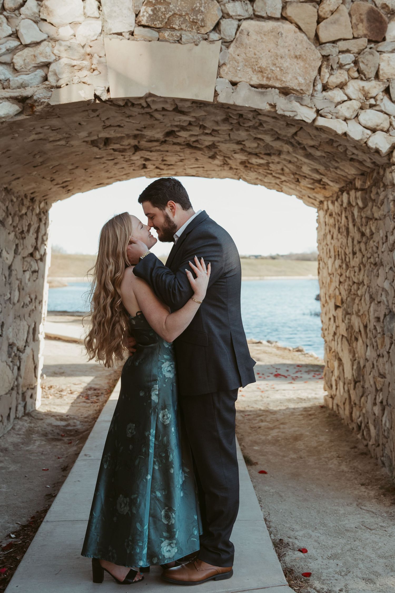 Romantic moment captured in stone archway overlooking coastal view.