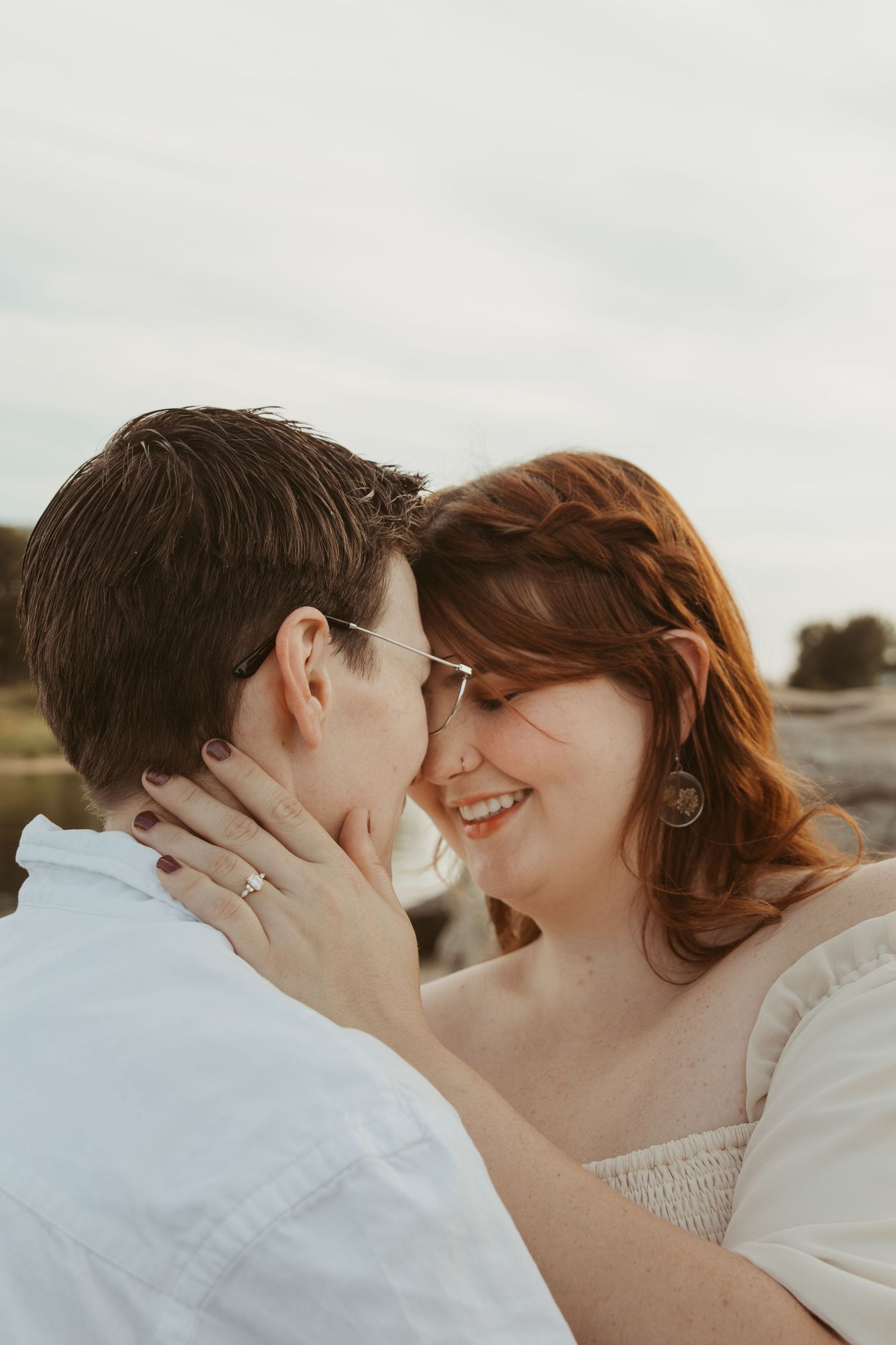 An intimate moment is shared between two people against a bright coastal backdrop.