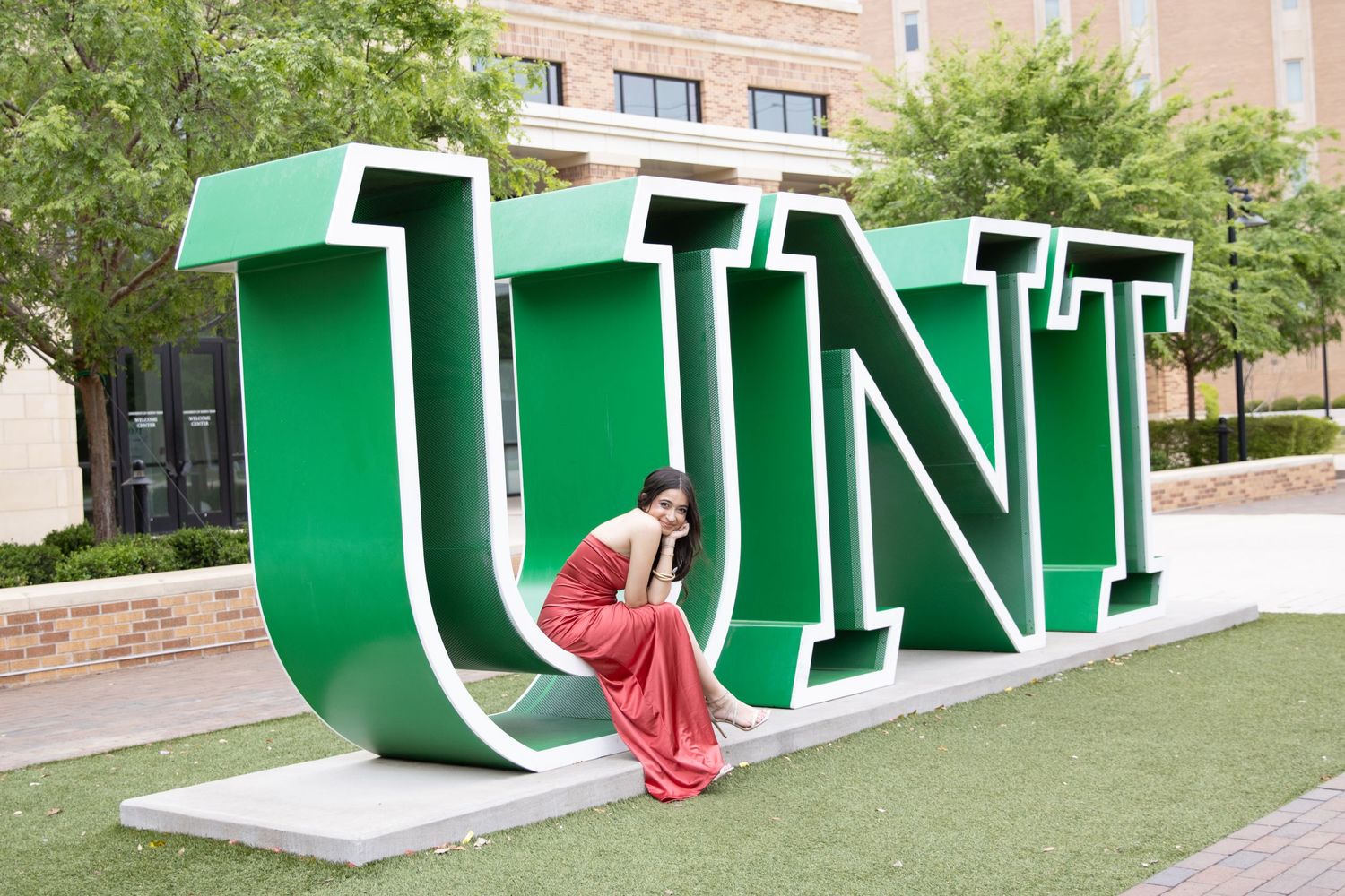 Large green UNT university letters installation on campus lawn.