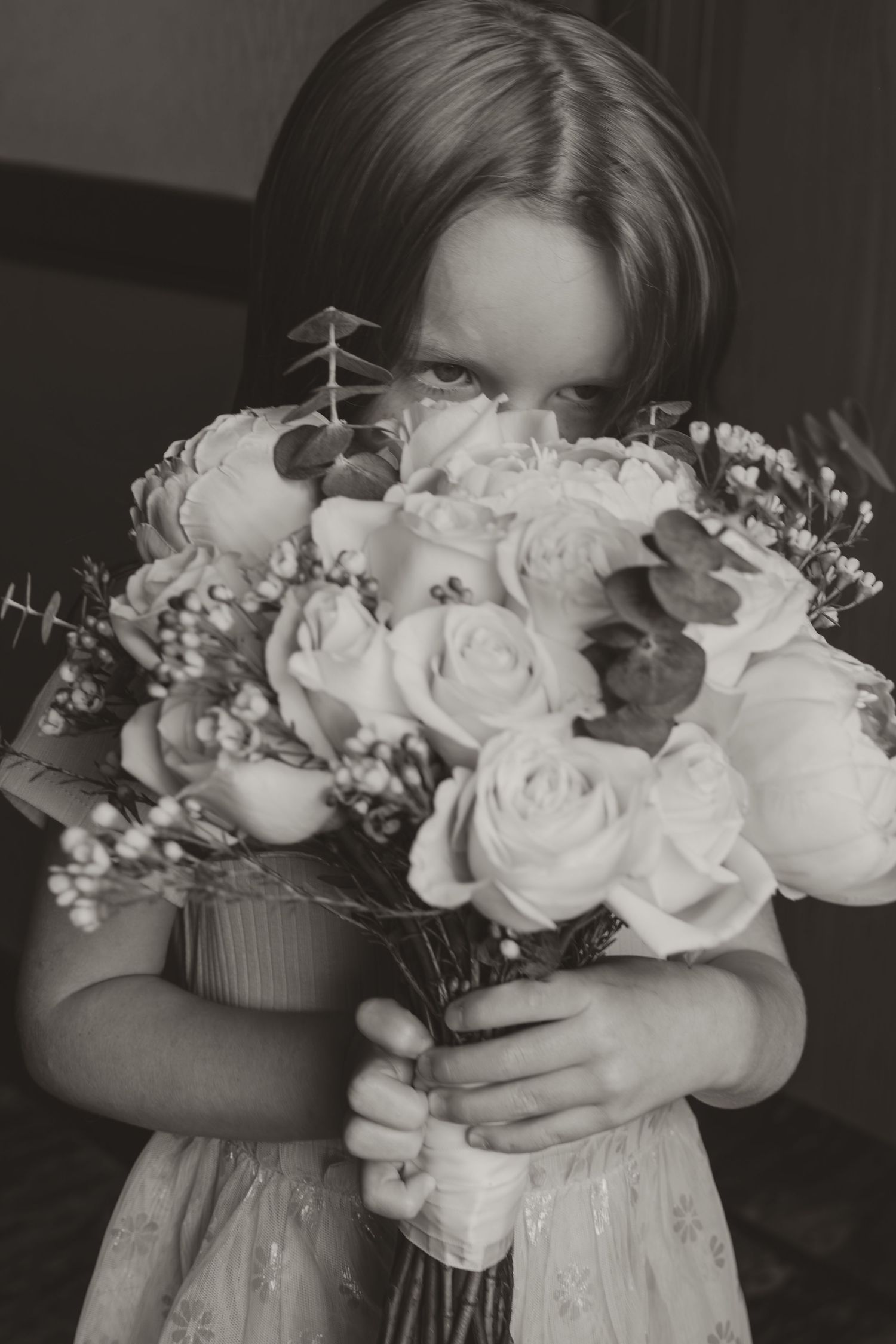 Close-up view of a white bridal bouquet with roses and baby's breath against a dark background.