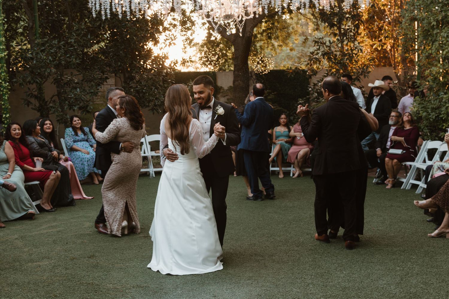 Guests gathered outdoors at dusk for a wedding reception in a garden setting.