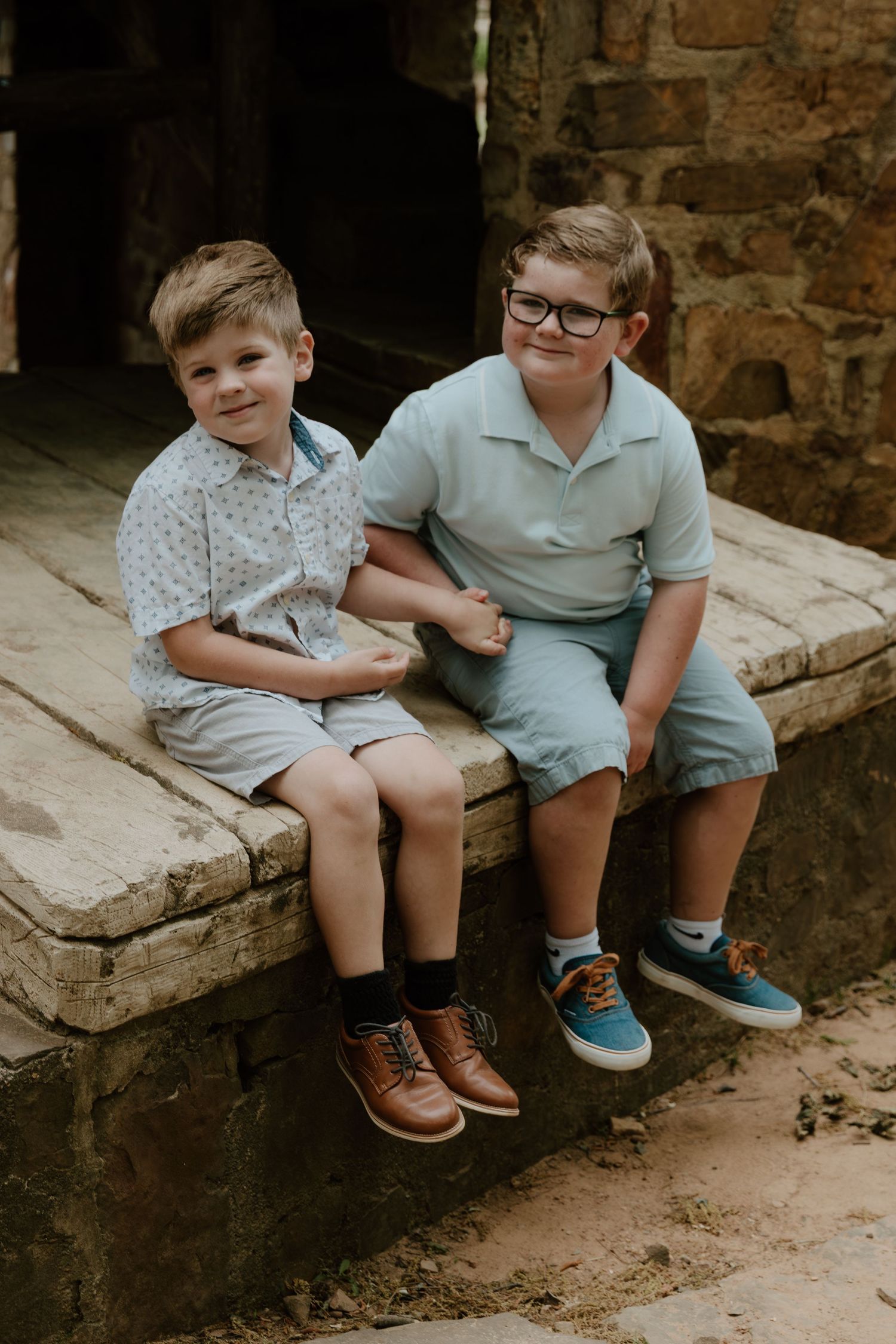 Two people sitting together on stone steps by an old brick entrance.