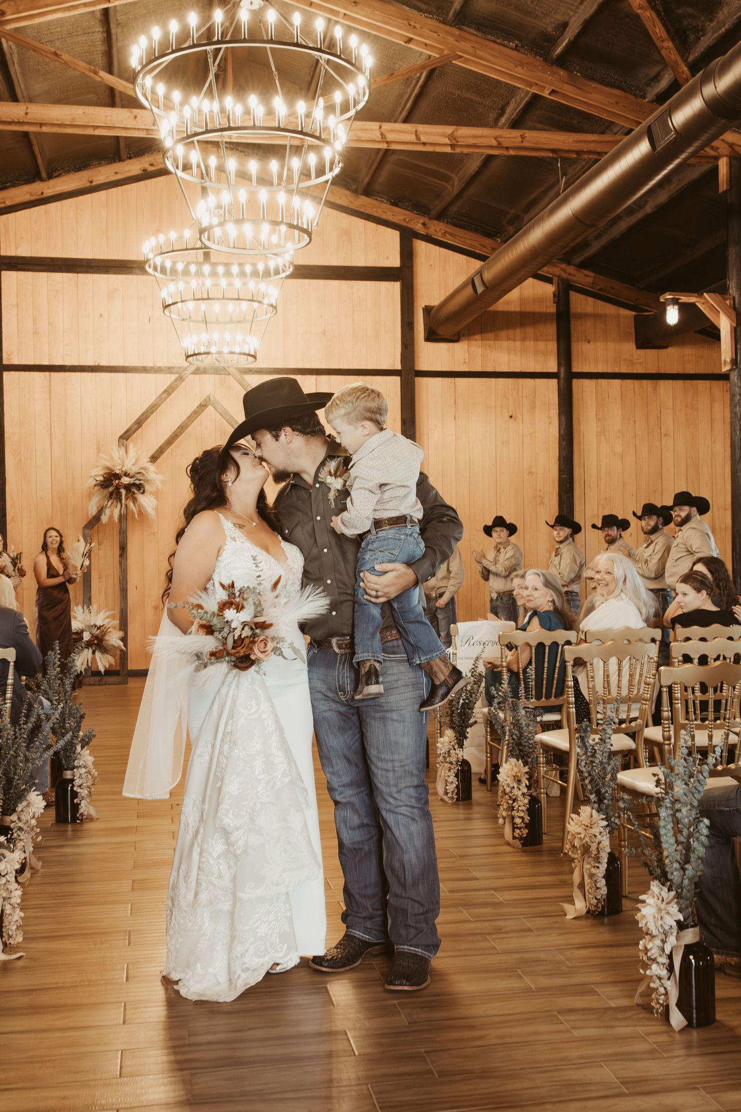 Wedding reception in a rustic barn with elegant chandeliers and wooden interior.  Wedding photographer DFW