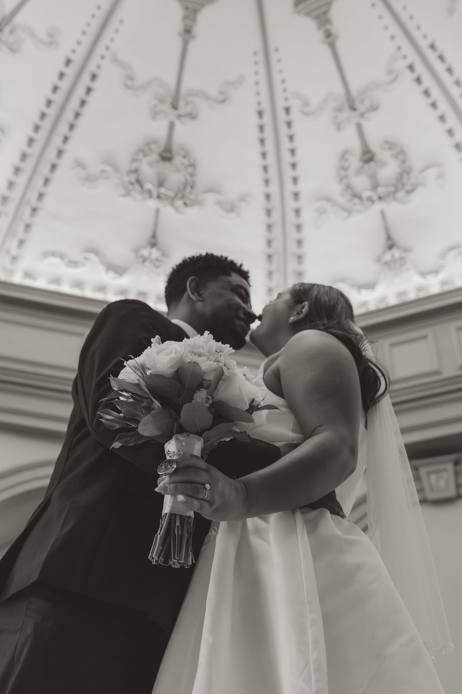 A sequence of black and white wedding photos showing a couple embracing under an ornate ceiling with decorative details. Wedding Photographe