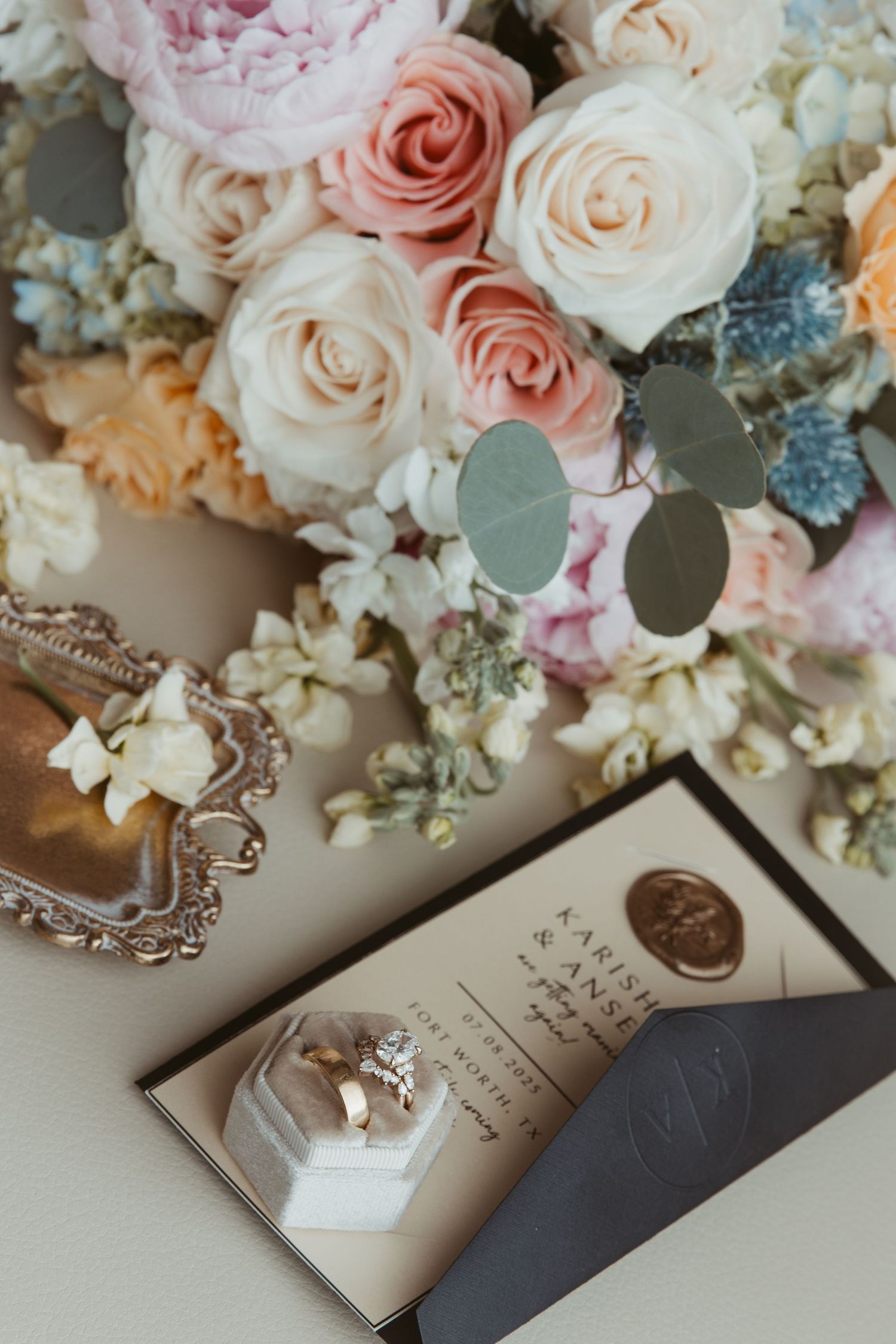 Romantic floral arrangement with pink and white roses alongside wedding stationery and decor items.