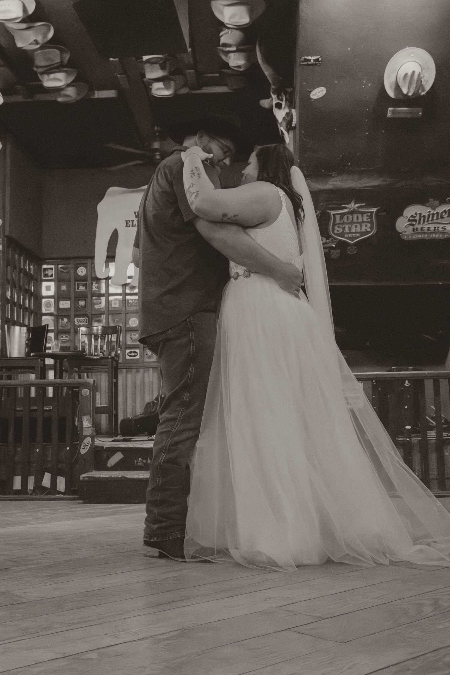 A romantic black and white dance scene with the bride's dress flowing on a wooden floor.