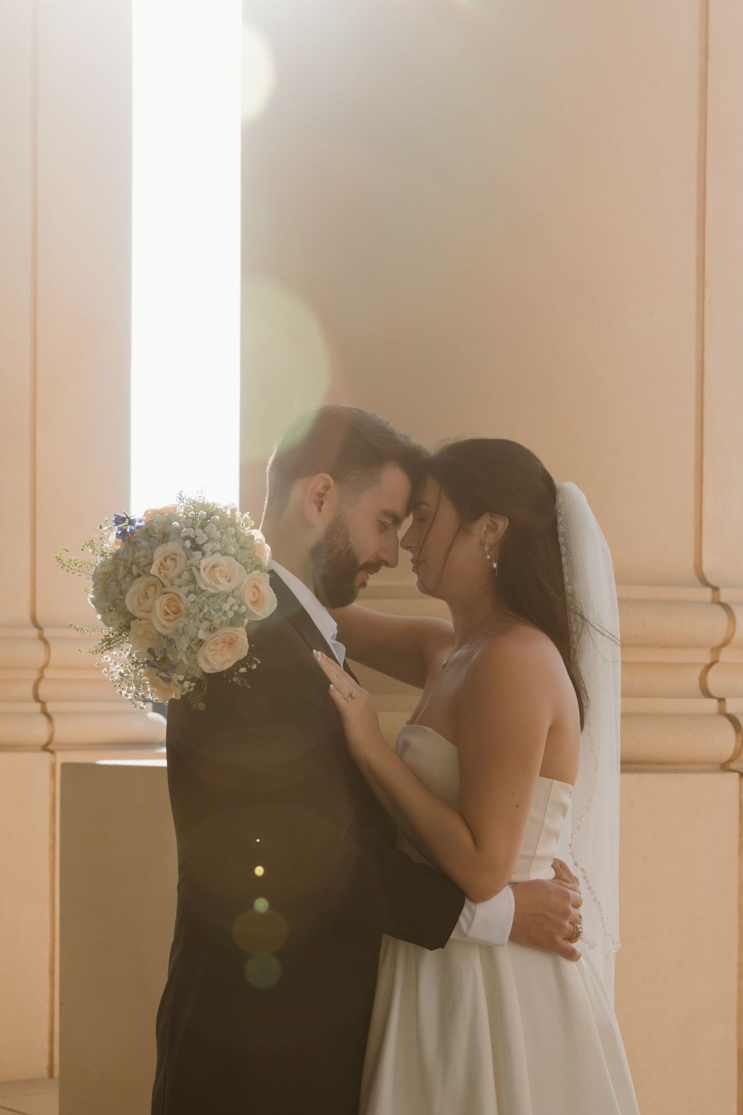 A romantic wedding sequence showing a couple kissing in front of elegant white columns with soft lighting and floral bouquet. Wedding Photog