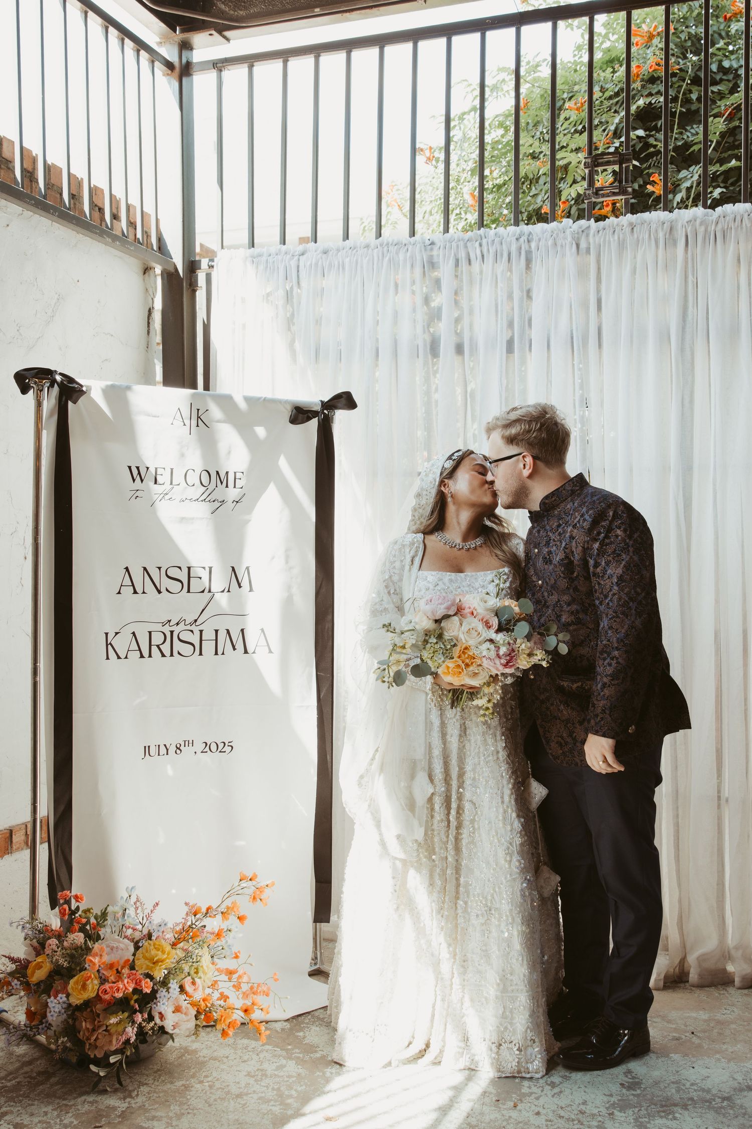 Modern wedding welcome sign and backdrop with floral arrangements.