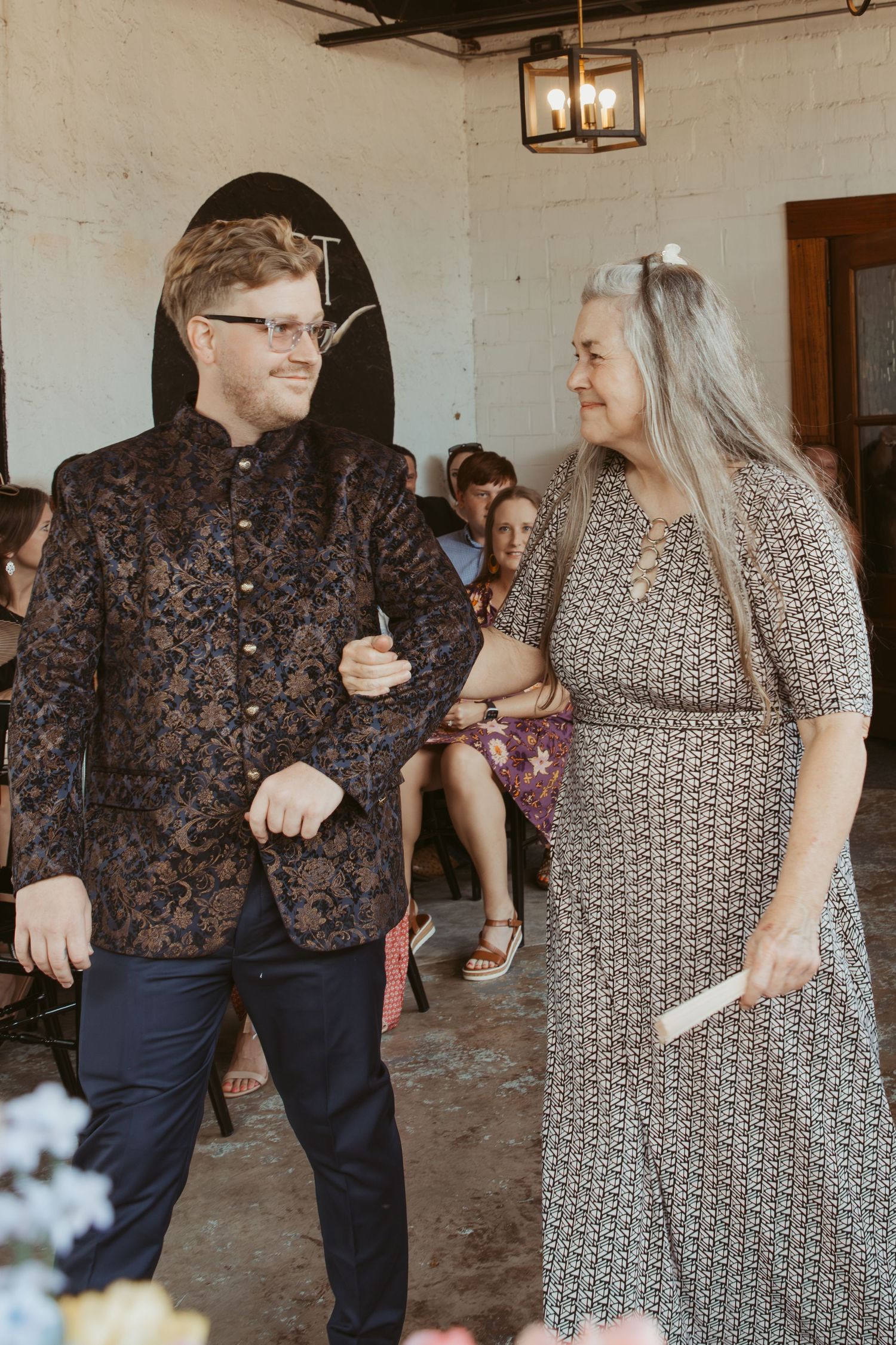 Guests in patterned attire dancing and socializing at a wedding reception.