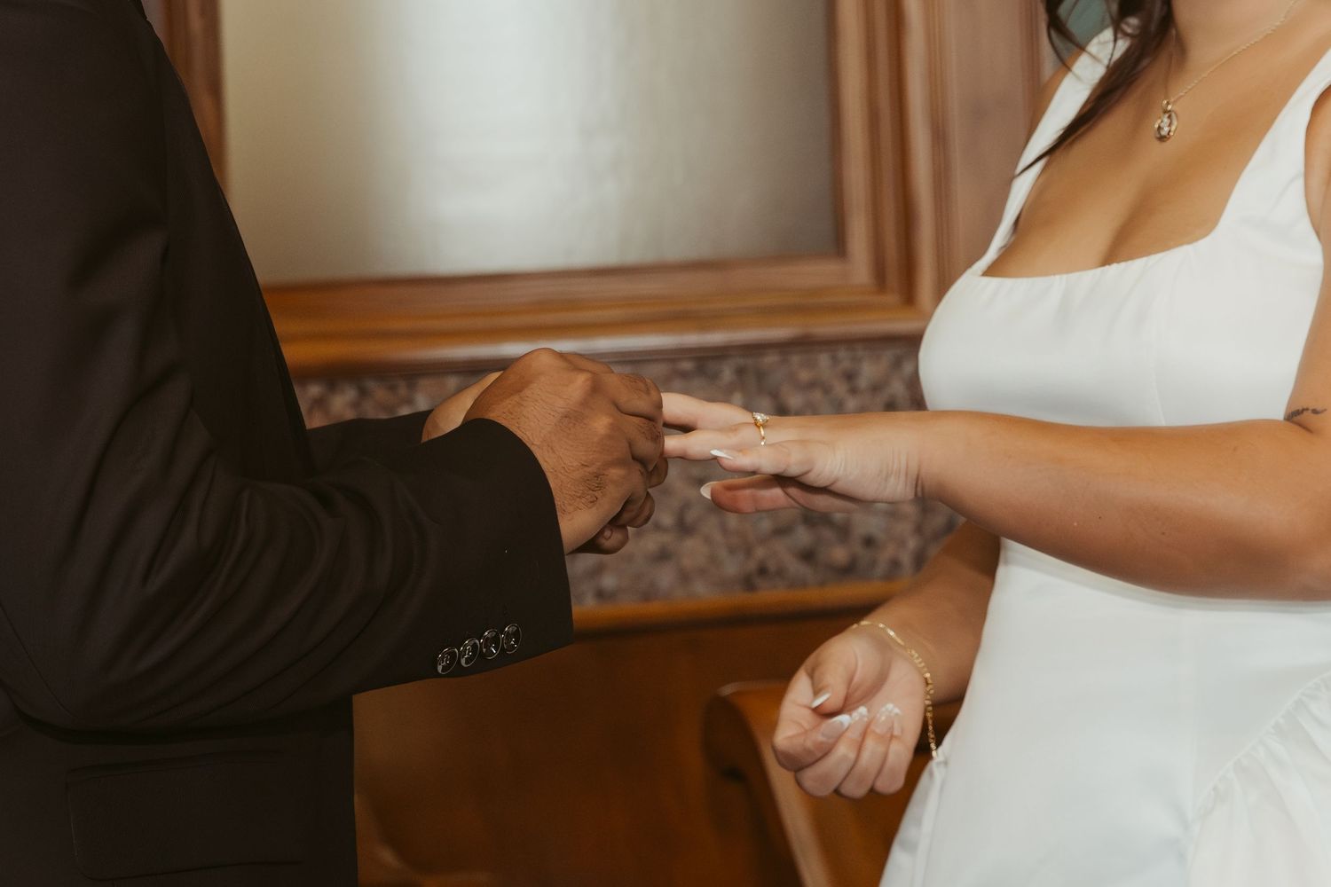 A couple holding hands during a wedding ceremony while exchanging rings at the altar. Wedding Photographer DFW