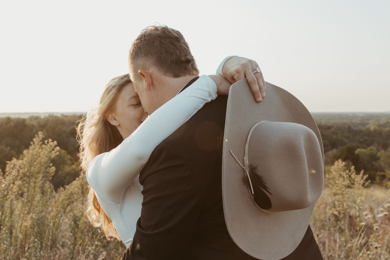 Romantic couple in formal attire embracing at sunset in a scenic outdoor setting. Engagement photographer DFW