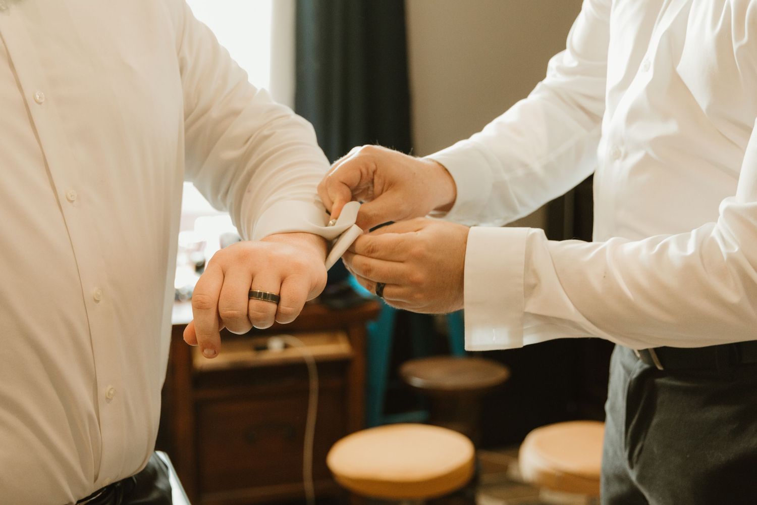 Close-up of hands adjusting cuff links on a white dress shirt sleeve.