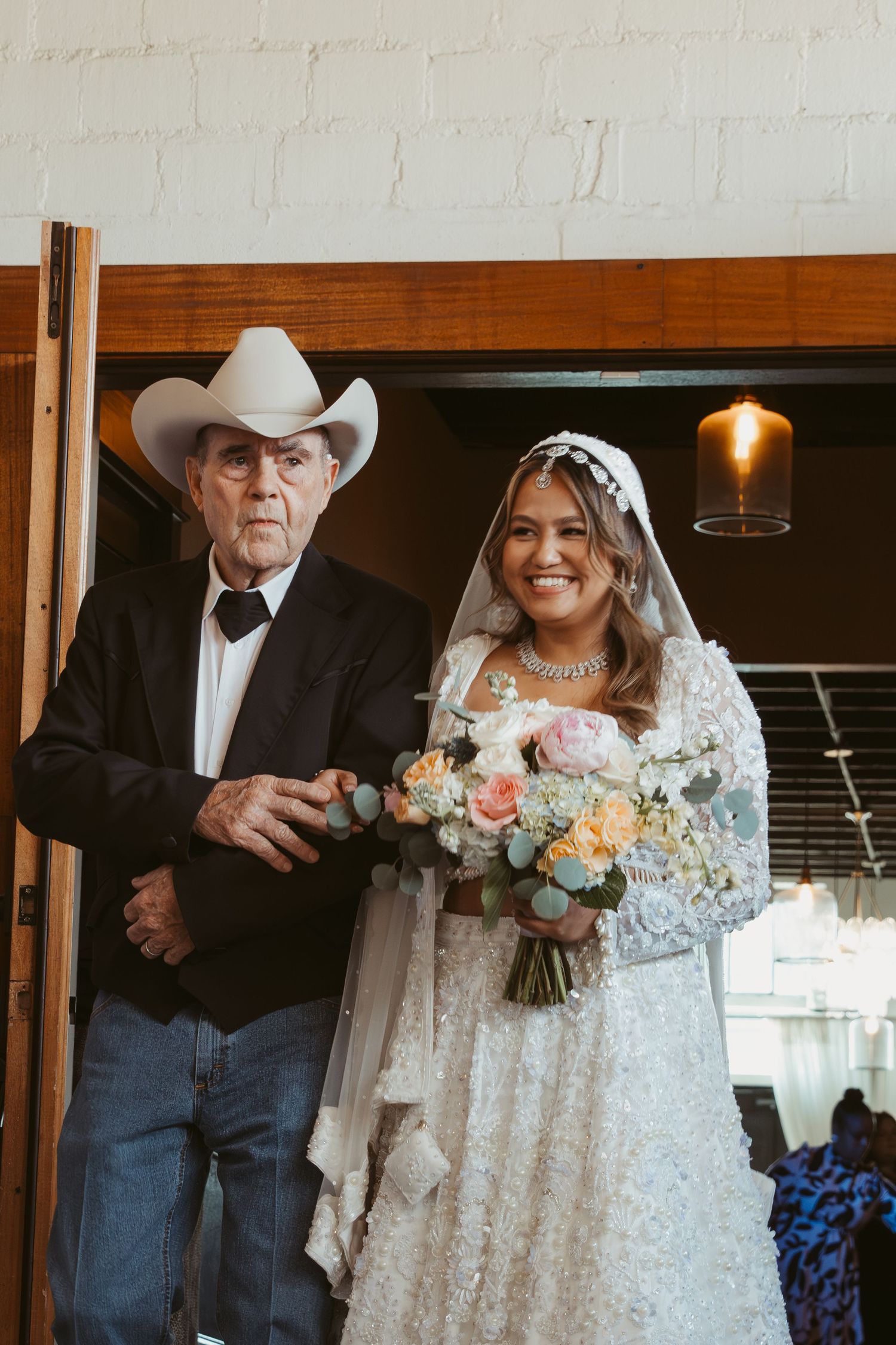 Wedding party in western attire with cowboy hats standing in a rustic venue.