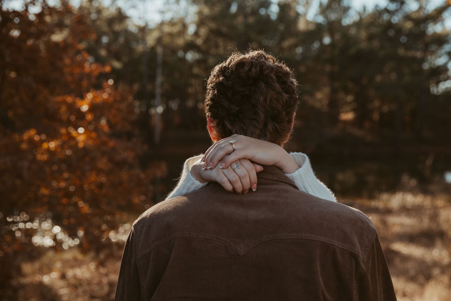 A couple embraces while watching a scenic autumn sunset in a rustic outdoor setting. engagement photos Fort Worth