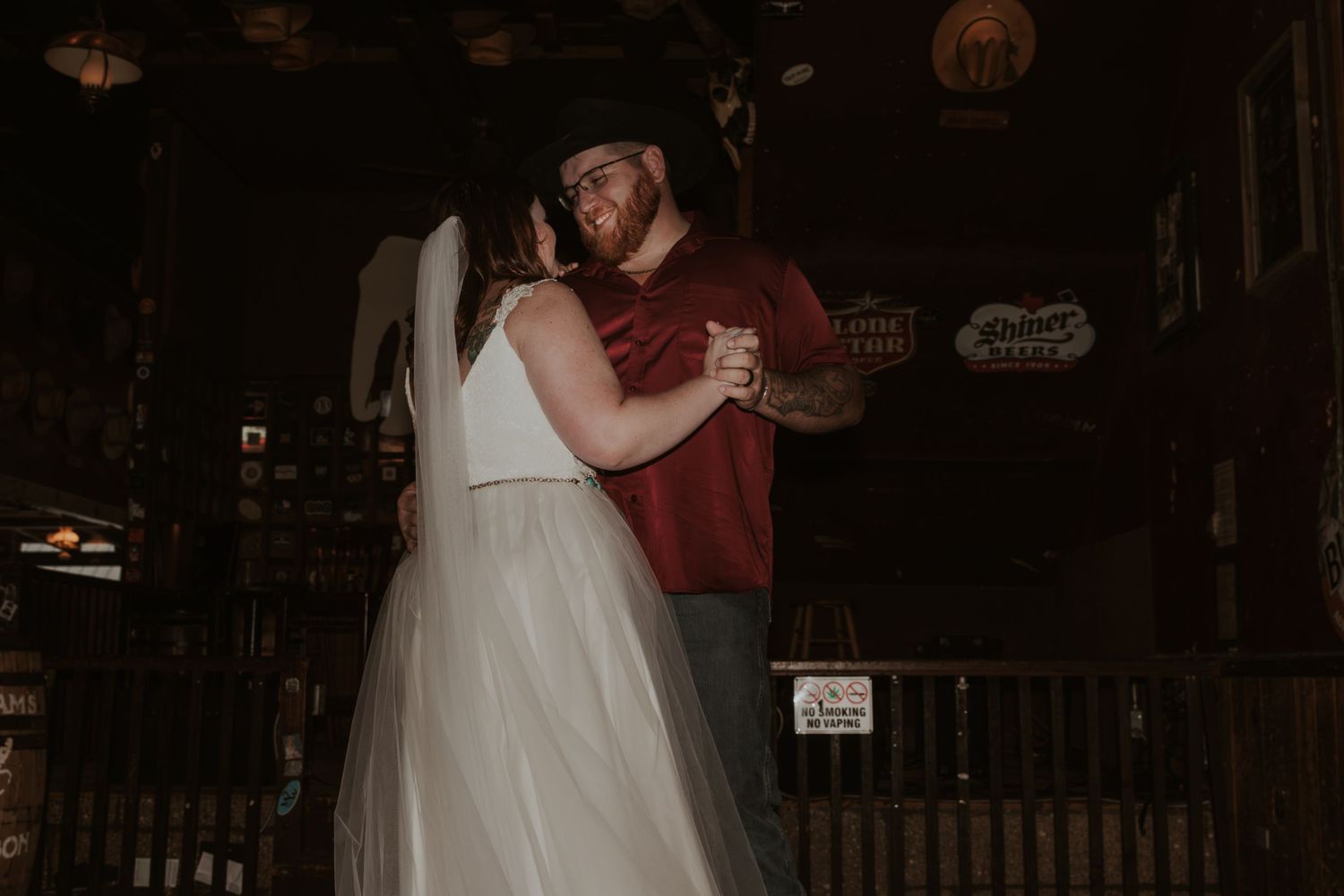A couple shares their first dance in a dimly lit venue with hanging lanterns.