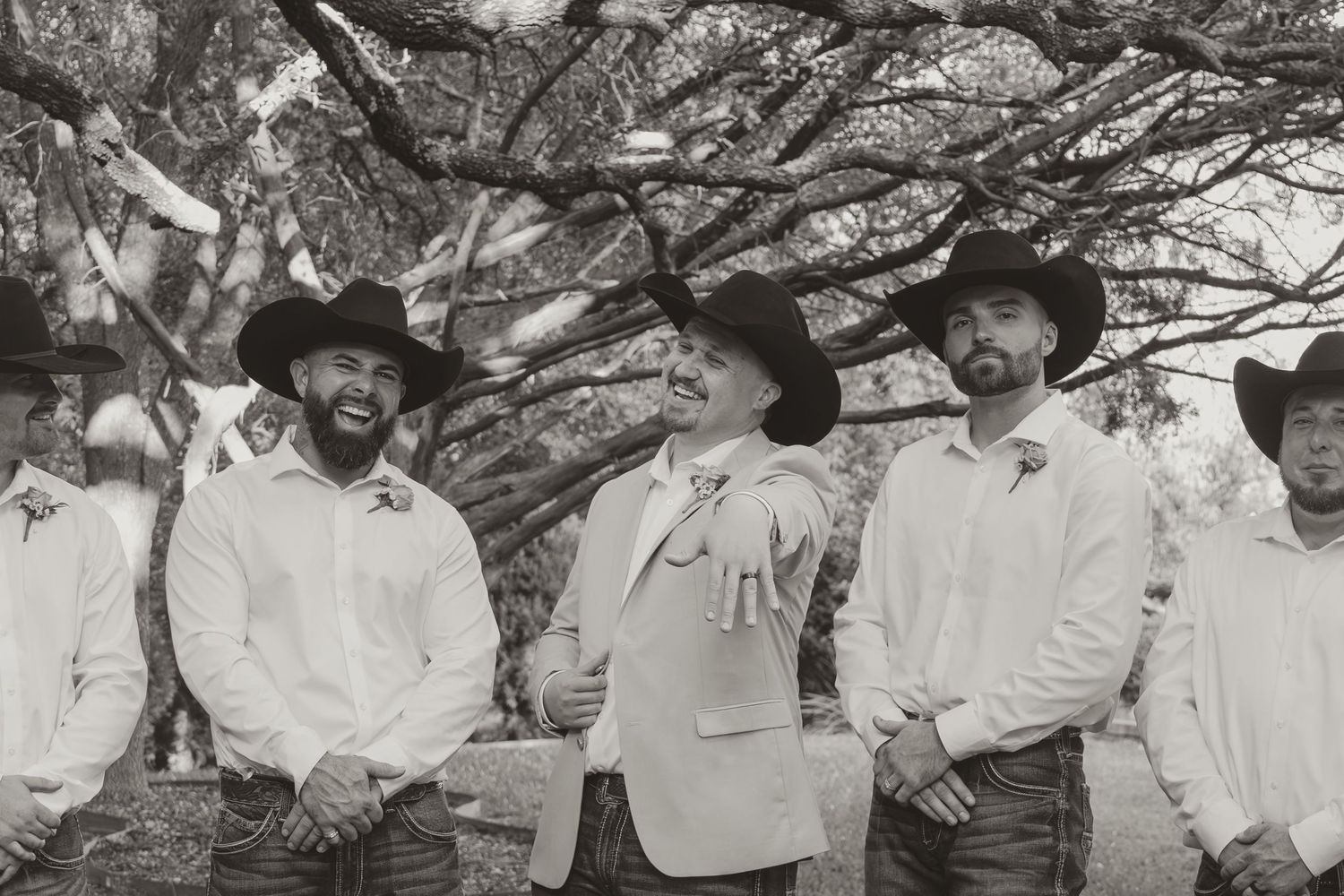 Black and white photograph showing a group of cowboys in white shirts and cowboy hats standing together outdoors. Wedding Photographer DFW