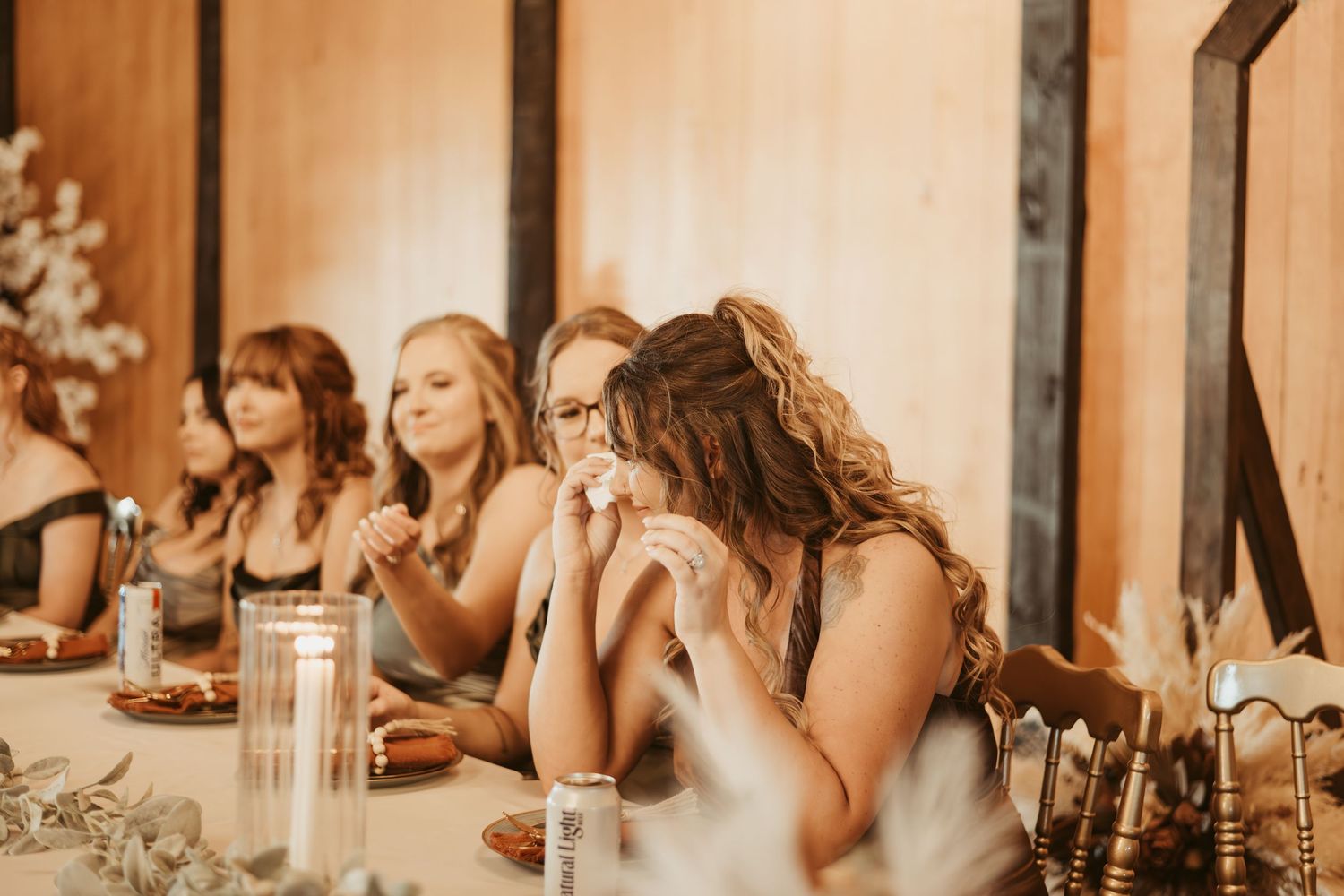 Wedding guests seated at long tables in a warm-lit reception venue. Wedding photographer DFW