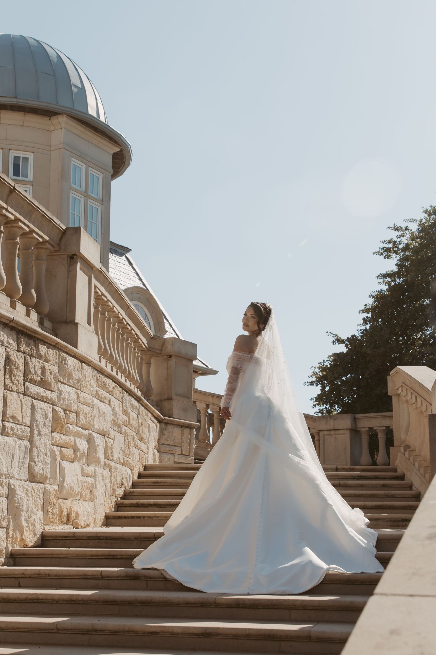 A dramatic wedding dress with full skirt photographed in sequence against stone architecture and stairs.