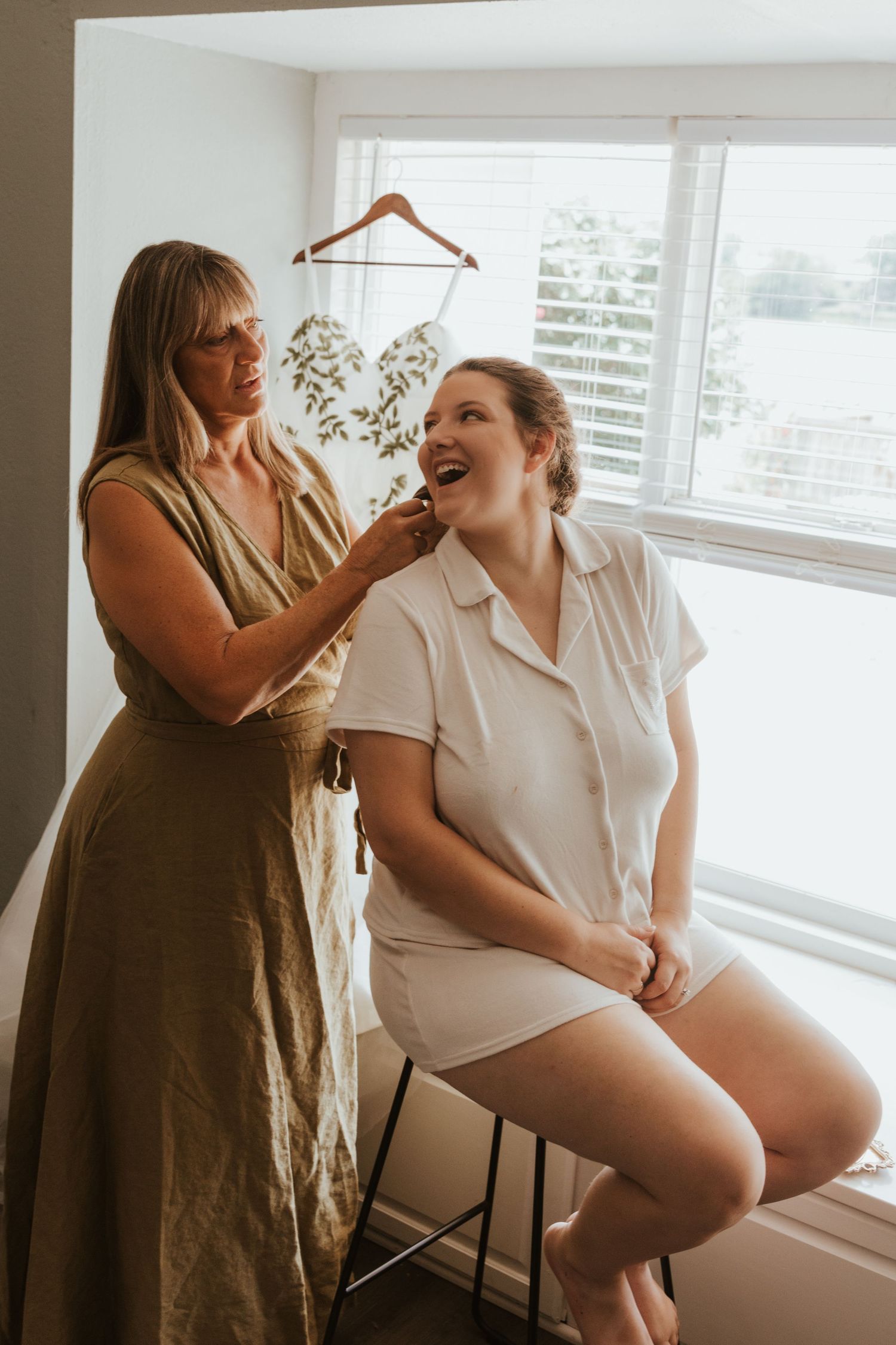 A tender getting ready moment during wedding preparations in a bright sunlit room.