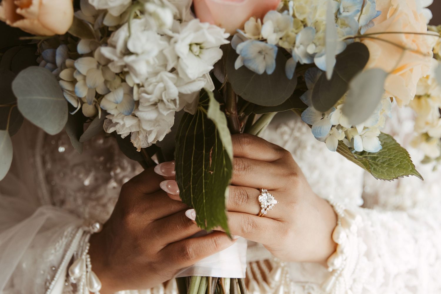 Close-up detail of a wedding bouquet featuring white hydrangeas and peach roses with greenery.
