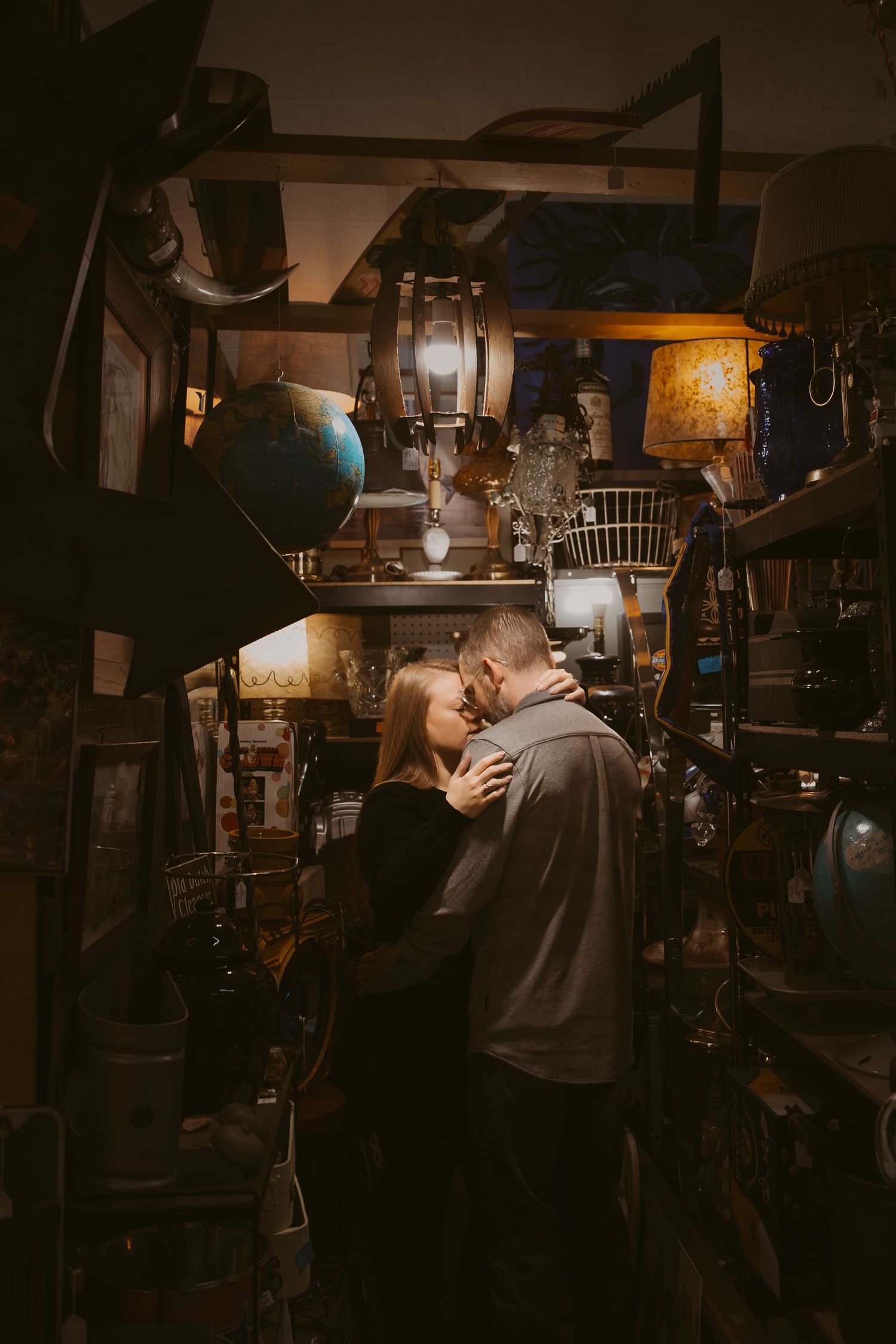 A romantic scene in a dimly lit antique shop filled with vintage machinery and industrial equipment.