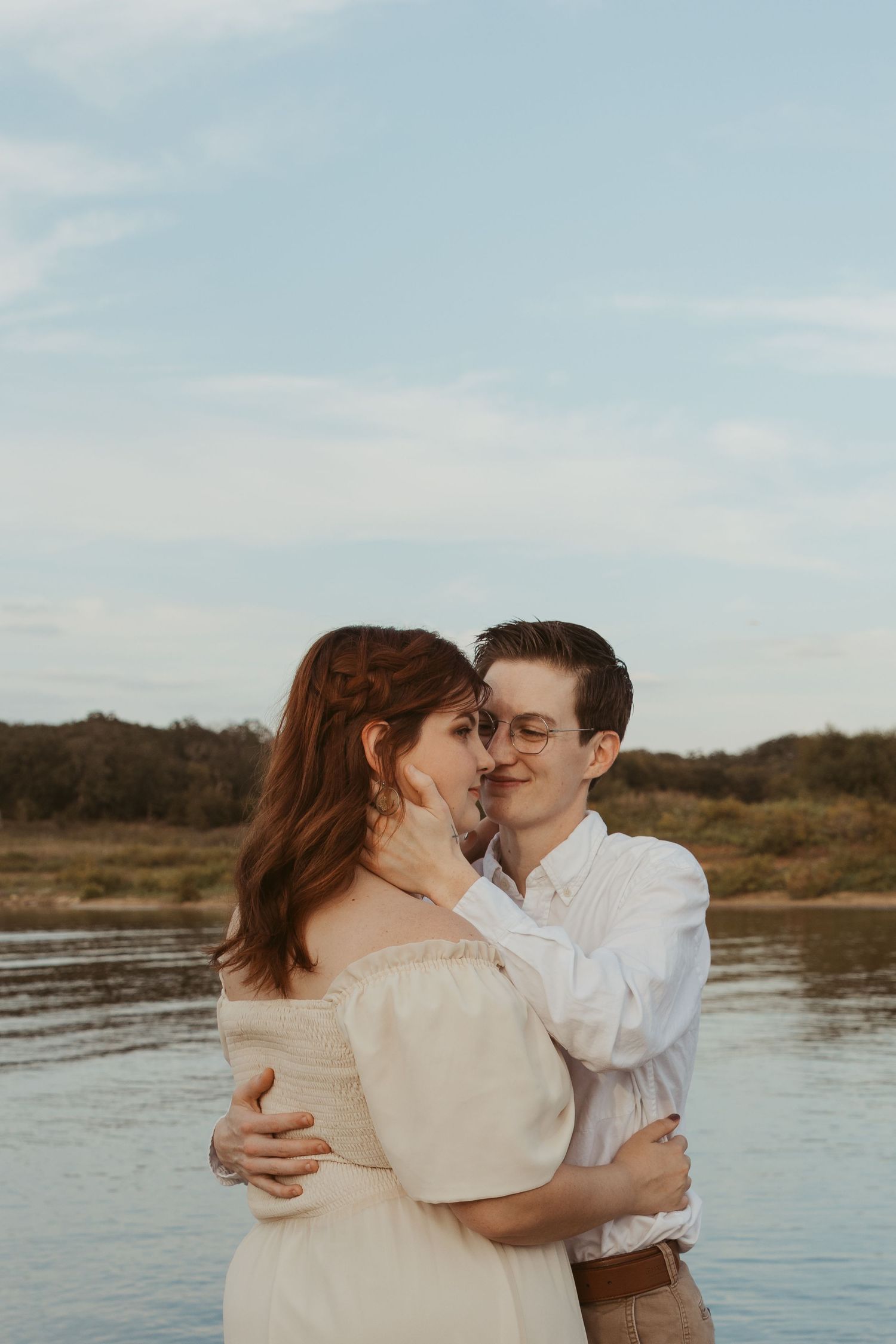 Romantic embrace by the water's edge during sunset photoshoot.