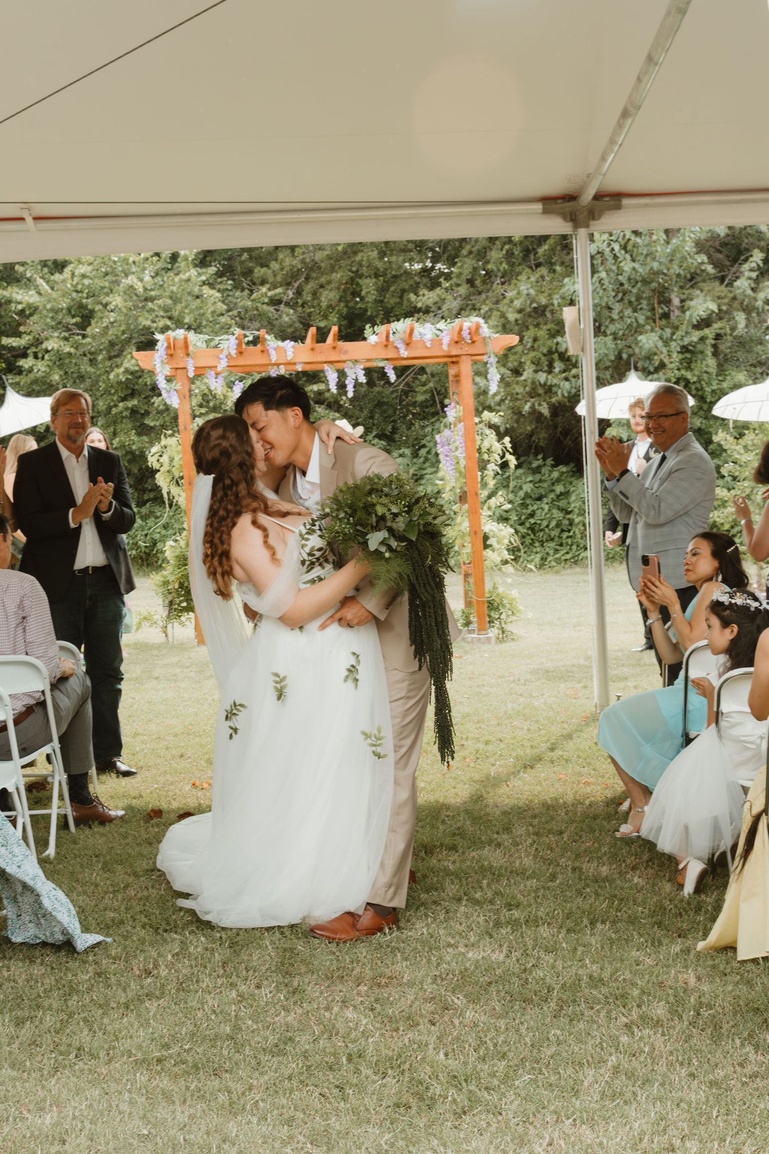 Newlyweds share their first dance under a tent at an outdoor reception.