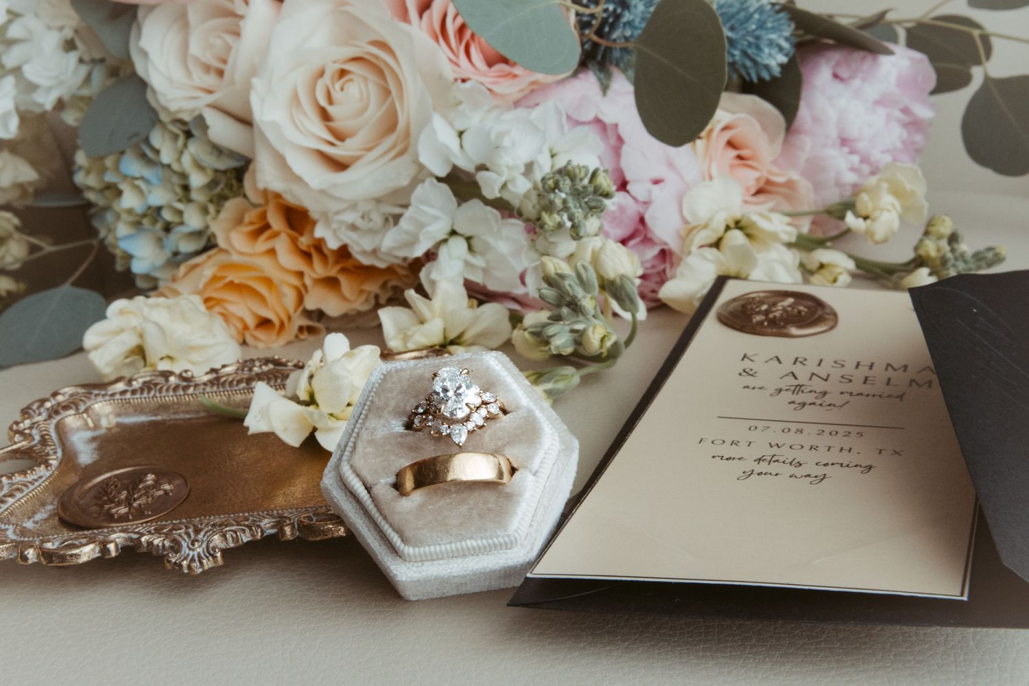 Delicate floral arrangements with peach and cream roses displayed alongside an elegant wedding invitation and details card.