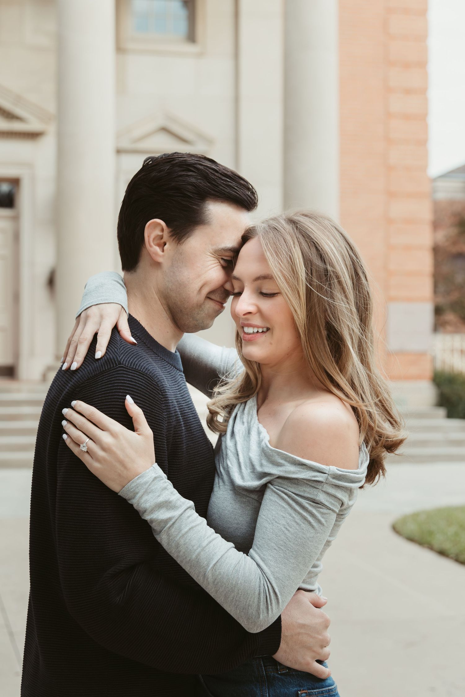A couple embracing and sharing tender moments outside a historic building.