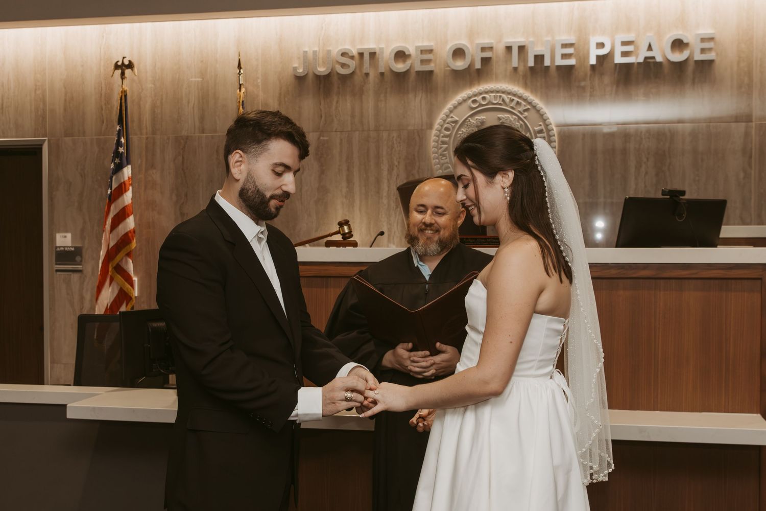 A romantic wedding ceremony moment captured in a courthouse with warm lighting and elegant decor. Wedding Photographer Fort Worth