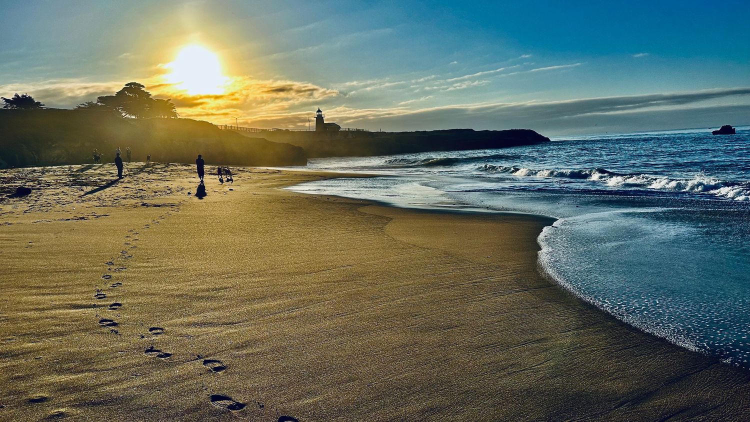 Scenic beach sunset with golden light, ocean waves, and sandy shore.