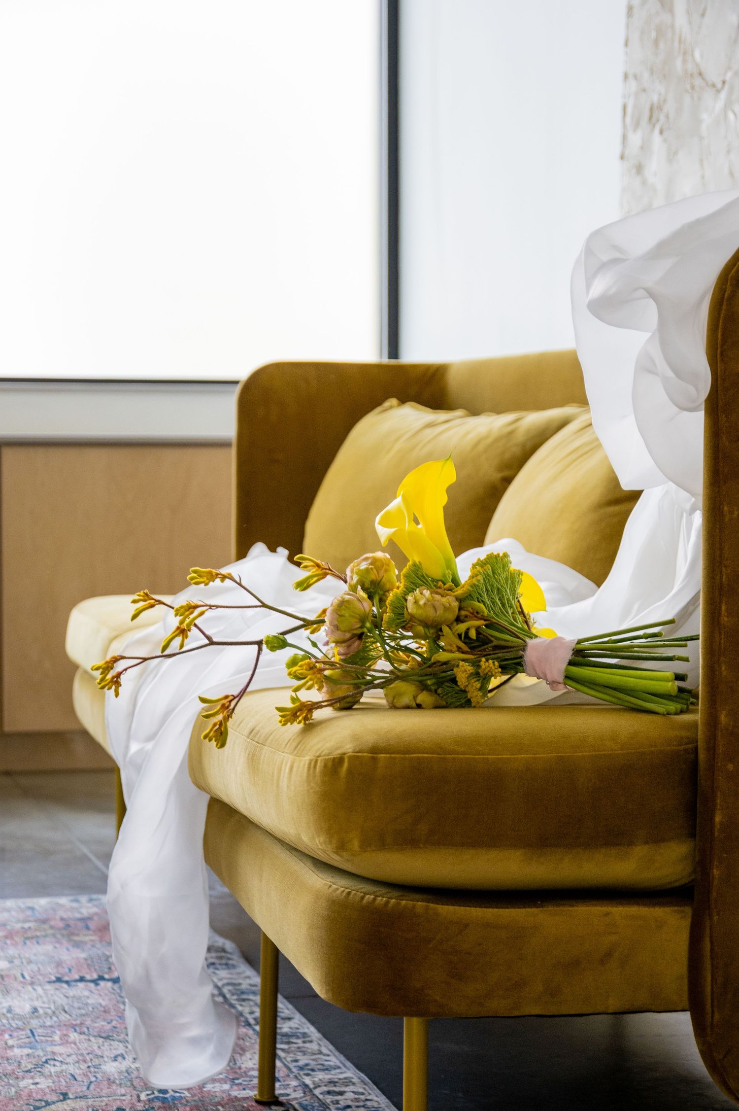 A yellow velvet sofa with white fabric and fresh yellow flowers arranged casually on its seat.