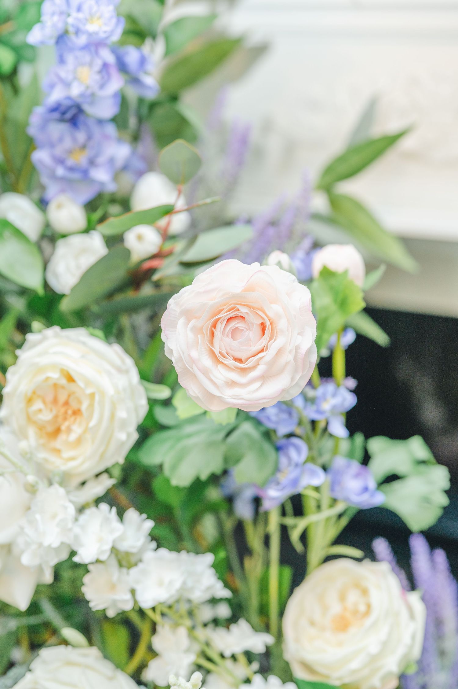 A soft arrangement of peach garden roses and delicate purple flowers with green foliage in a romantic floral display.