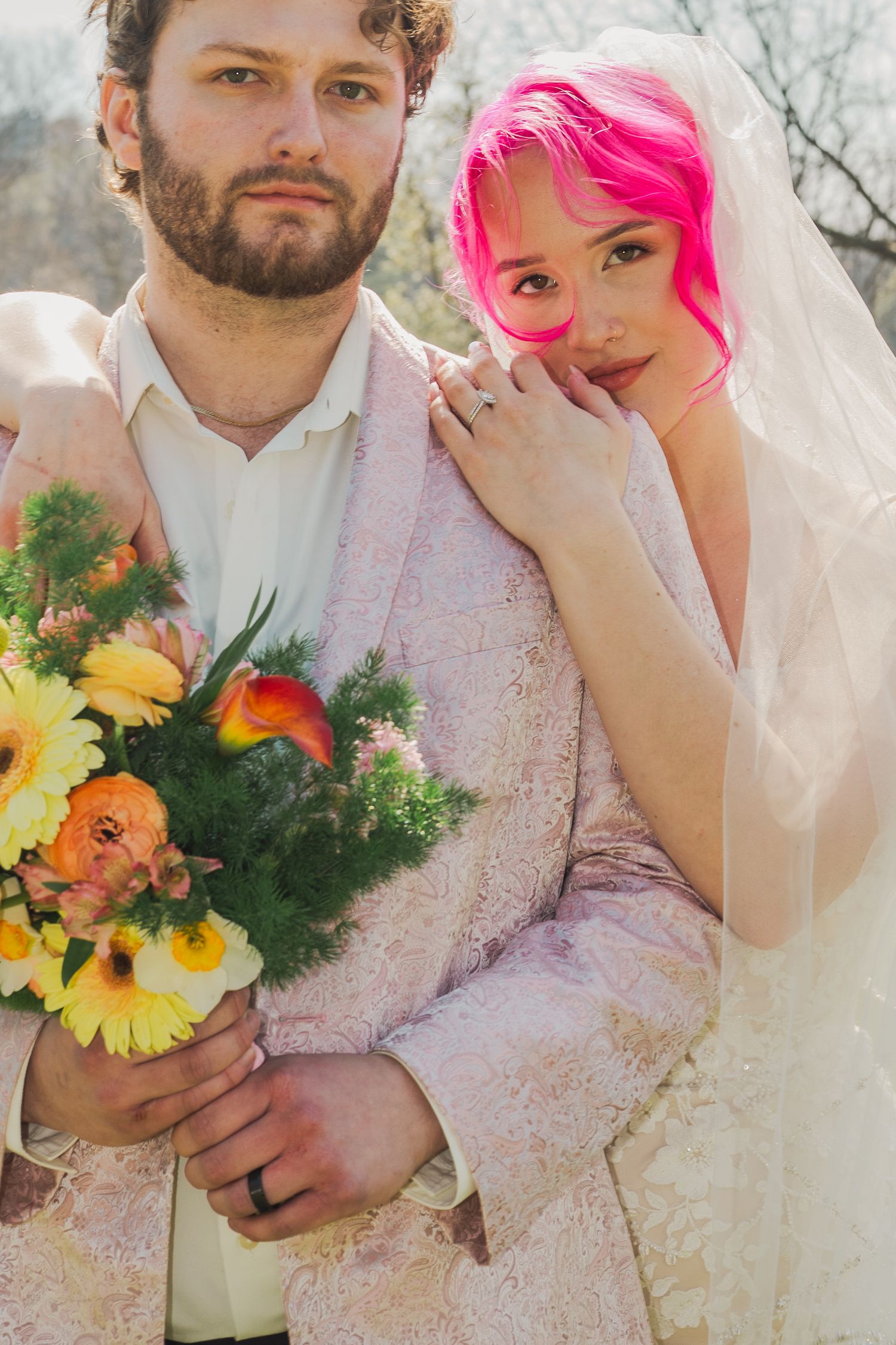 A wedding couple poses with bright sunflowers and orange flowers in a series of romantic outdoor portraits.