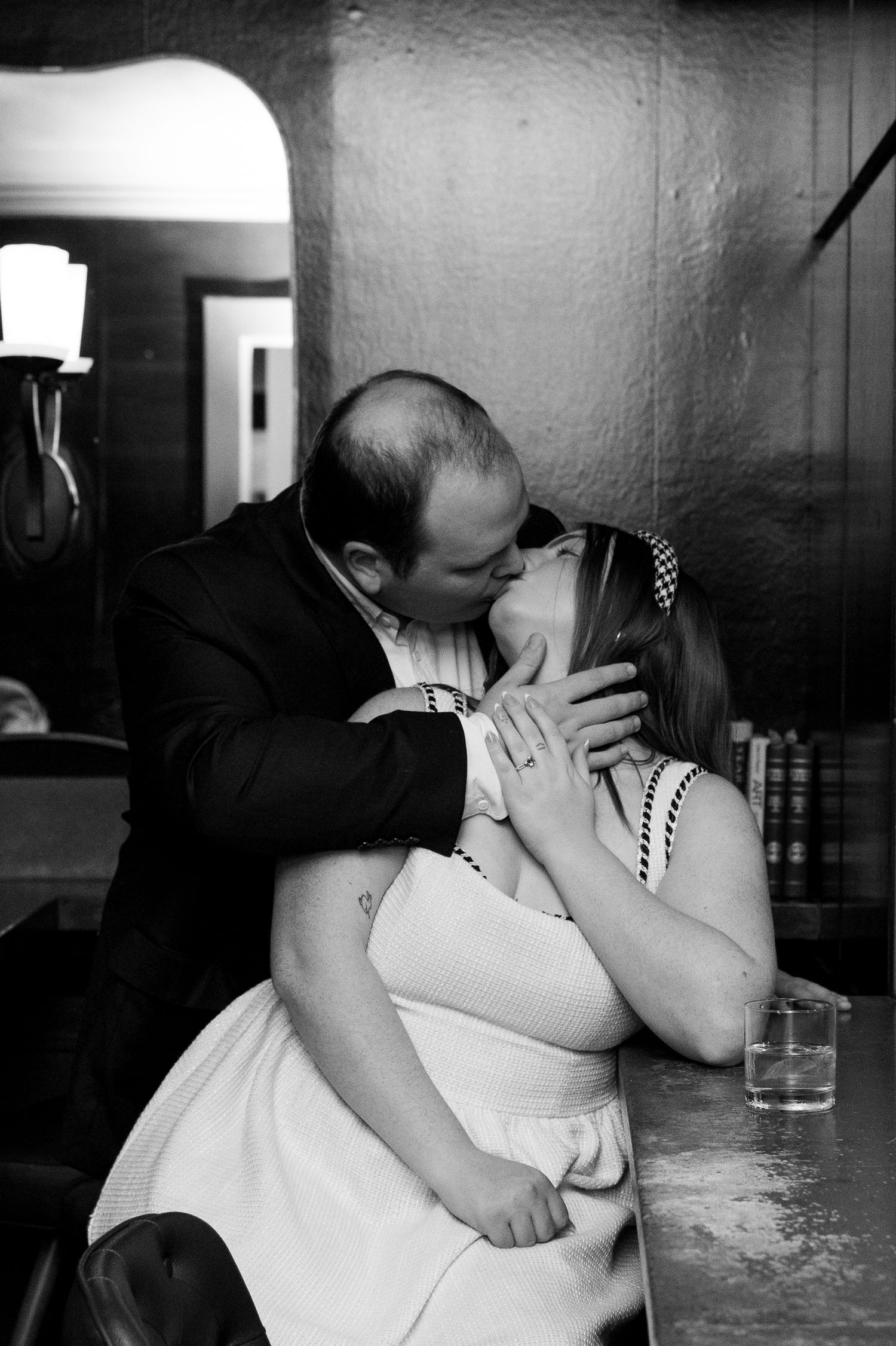 A sequence of black and white photographs showing a couple sharing intimate kisses at a bar counter.