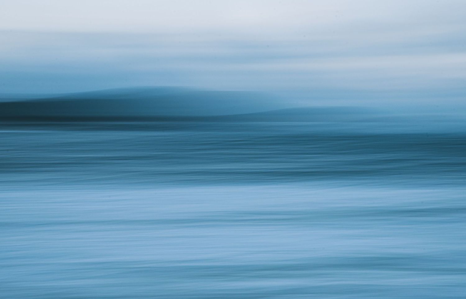 Minimalist seascape with smooth blue ocean horizon creating abstract lines.