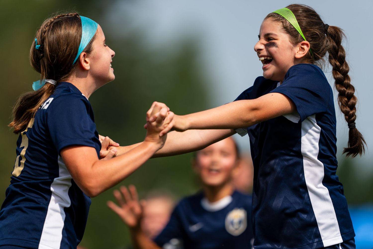 A young female soccer player celebrating with her teammates after scoring a goal.
