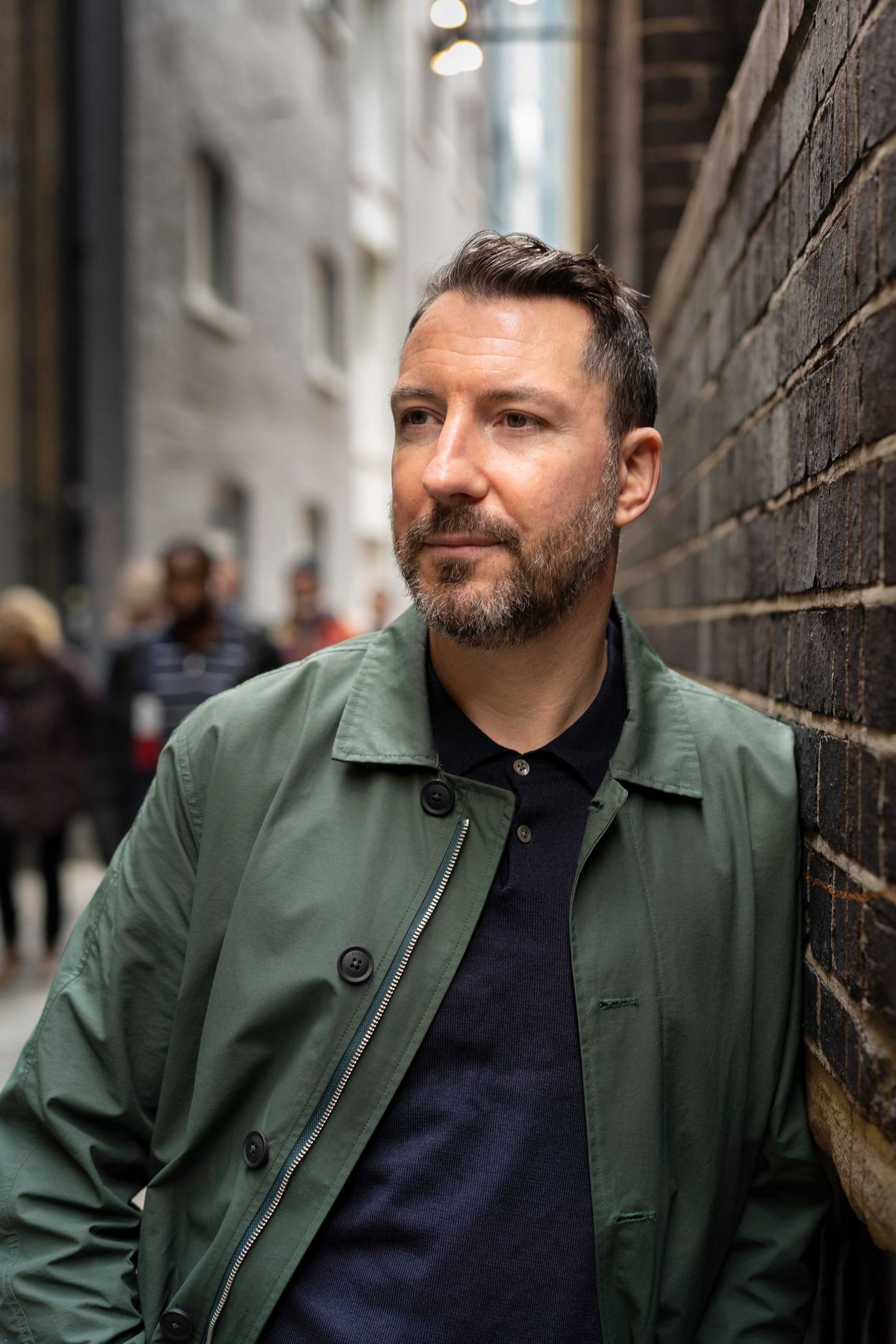 A London business owner leans against a brick wall during his personal branding photo shoot on the South Bank, London.