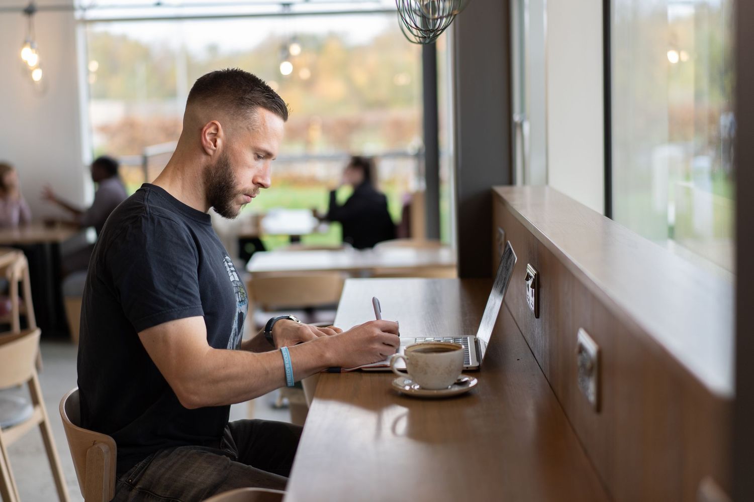 The coffee shop copywriter sits making notes on his personal brand photoshoot in Whiteley, Fareham.