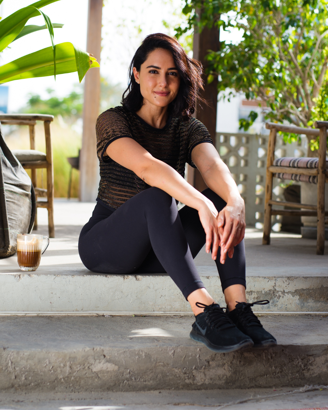 Dubai-based wellness coach sits on a step with a coffee during her personal branding photography session.
