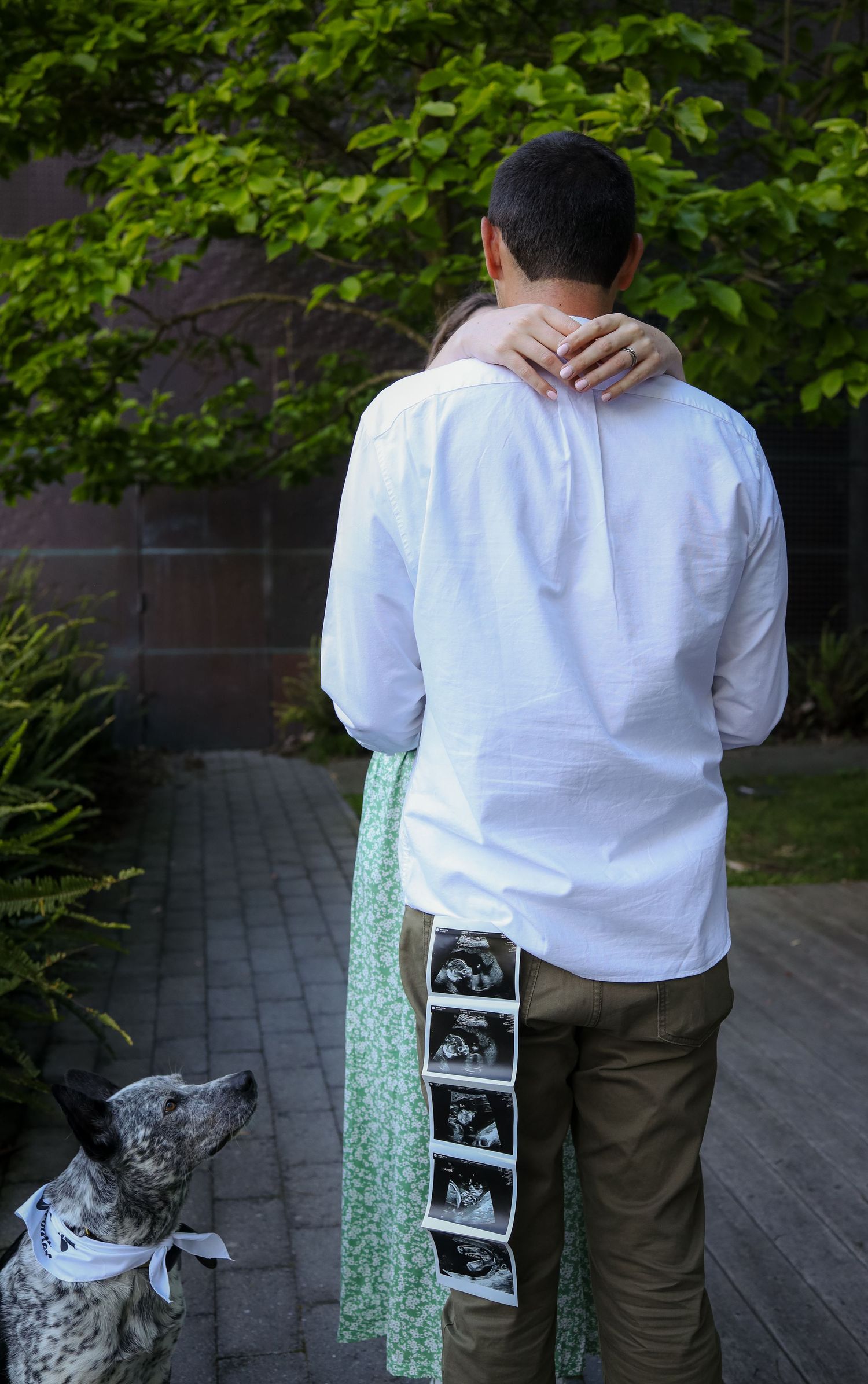 Close-up detail shot of expecting couple holding ultrasound sonogram strip in golden light, creative baby announcement photography in SF