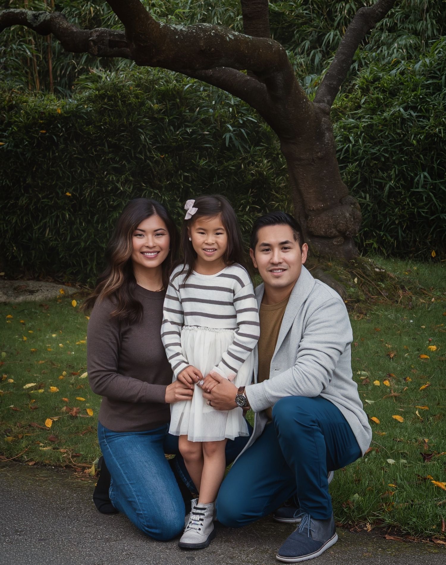 Soft, unscripted portrait of mother and father sitting on the grass with their daughter in Golden Gate Park, San Francisco.