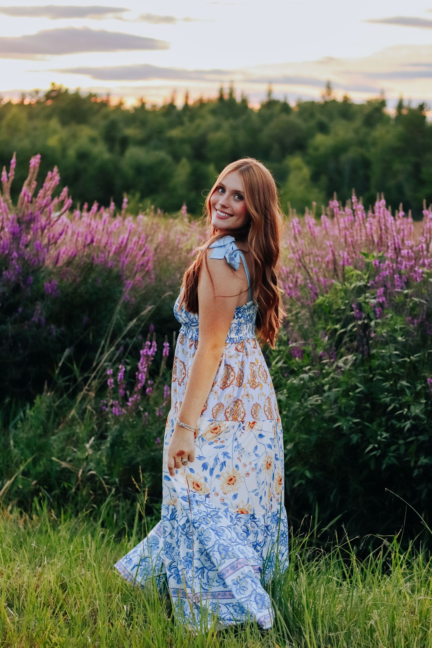 A solo female portrait session in a field of purple lupines during sunset.