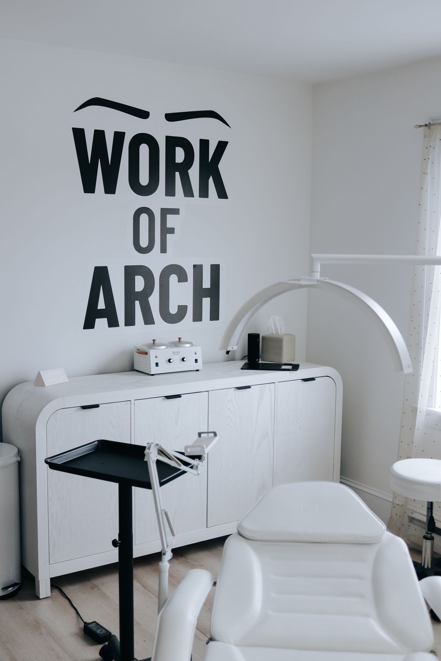 Minimalist white interior design featuring sleek furniture and black text wall art in a bright, modern space.
