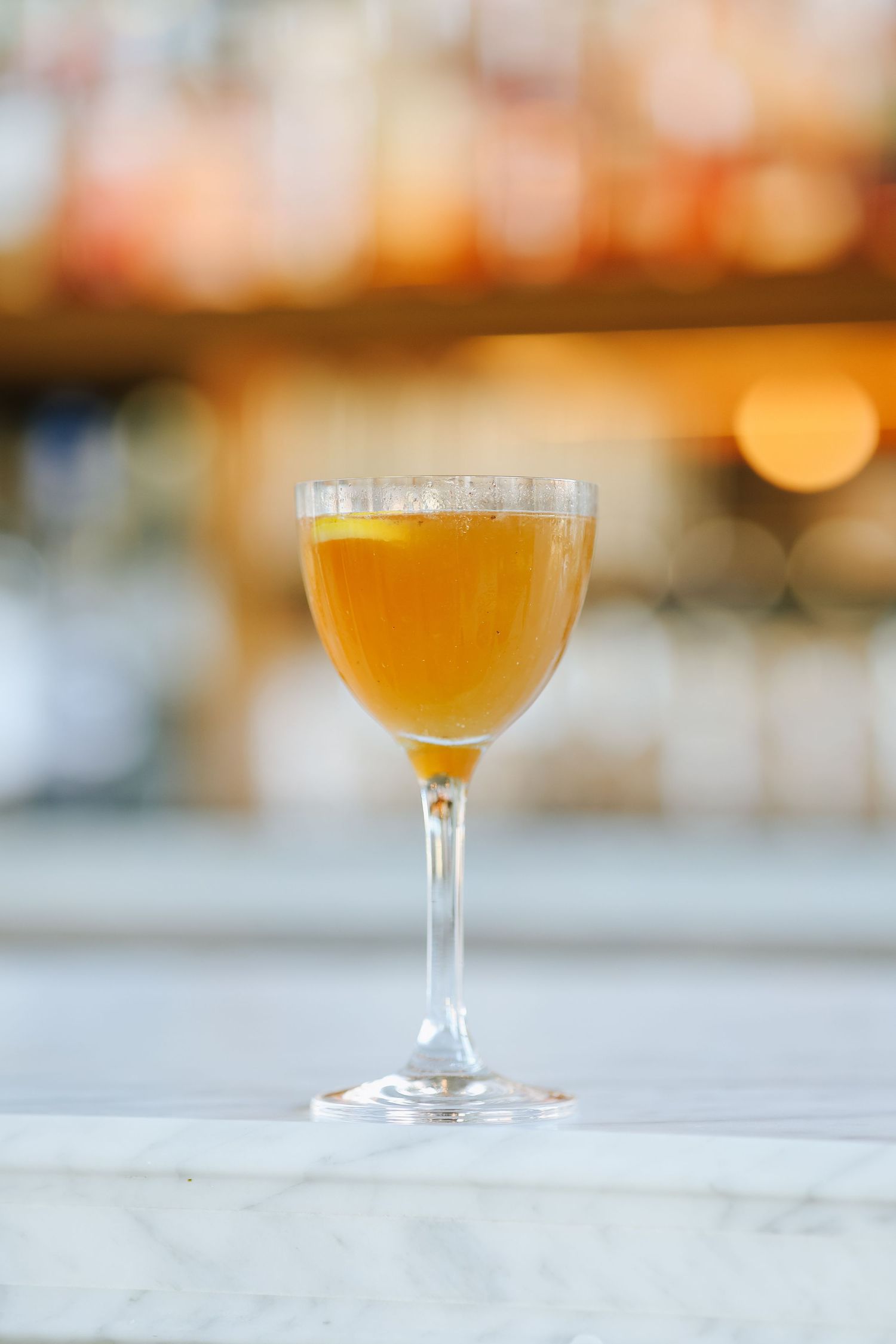 Three stemmed glasses filled with golden craft beer sit on a white surface with warm bokeh lighting in the background.