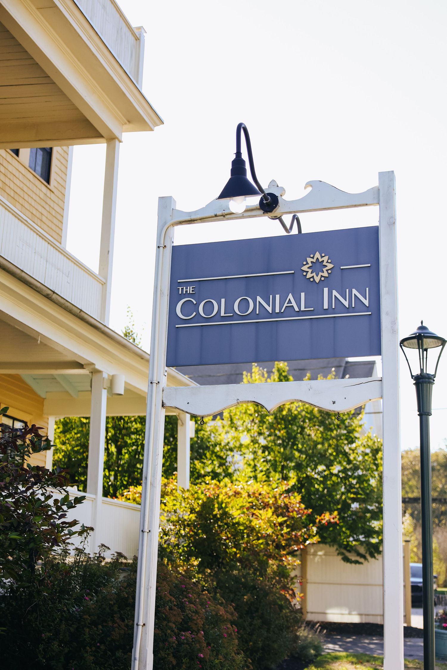 Close-up views of a navy blue and white Colonial Inn sign with classic lamp post against a sunny sky background.