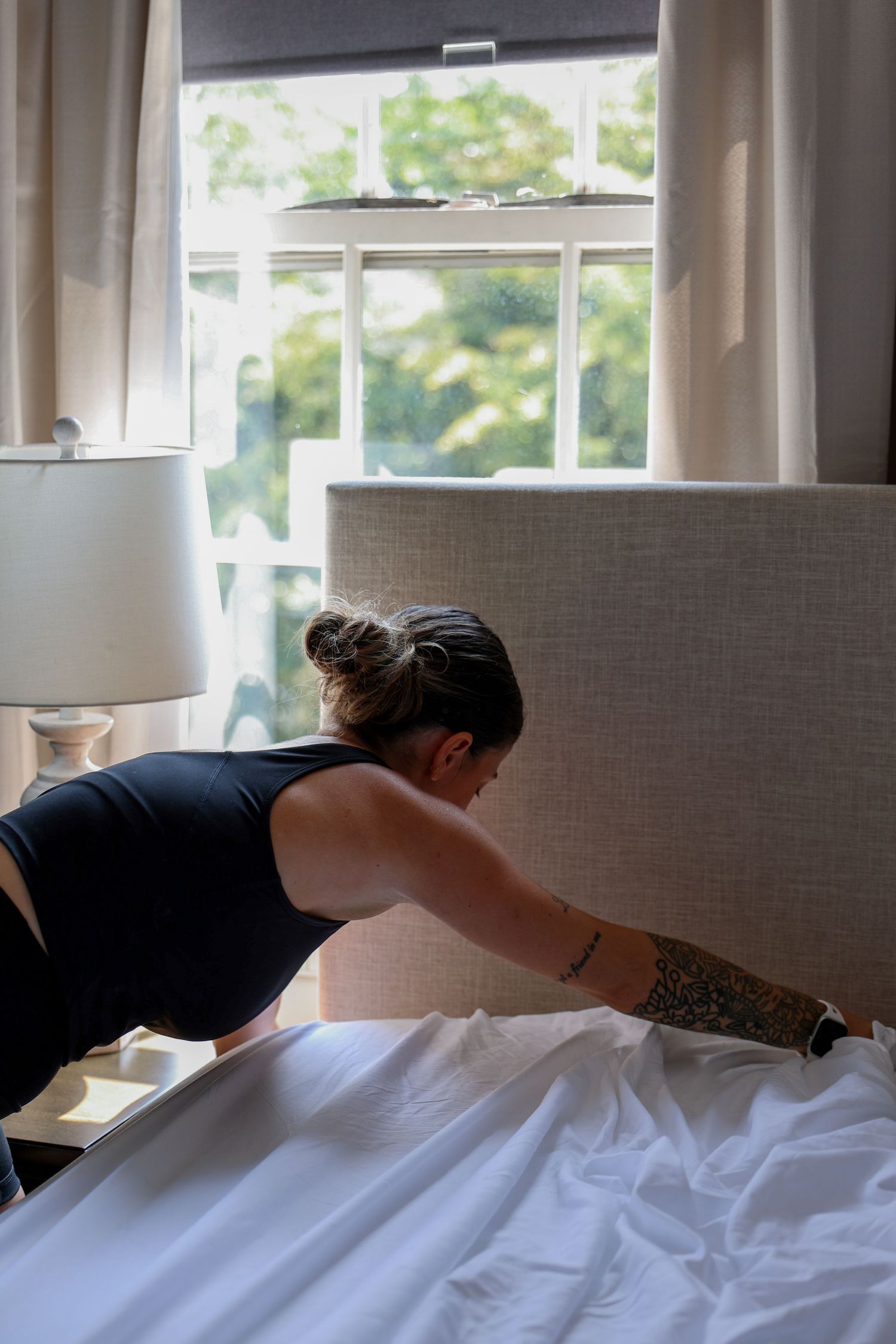 A sequence of images showing someone making a bed with white sheets and pillows in a sunlit bedroom.