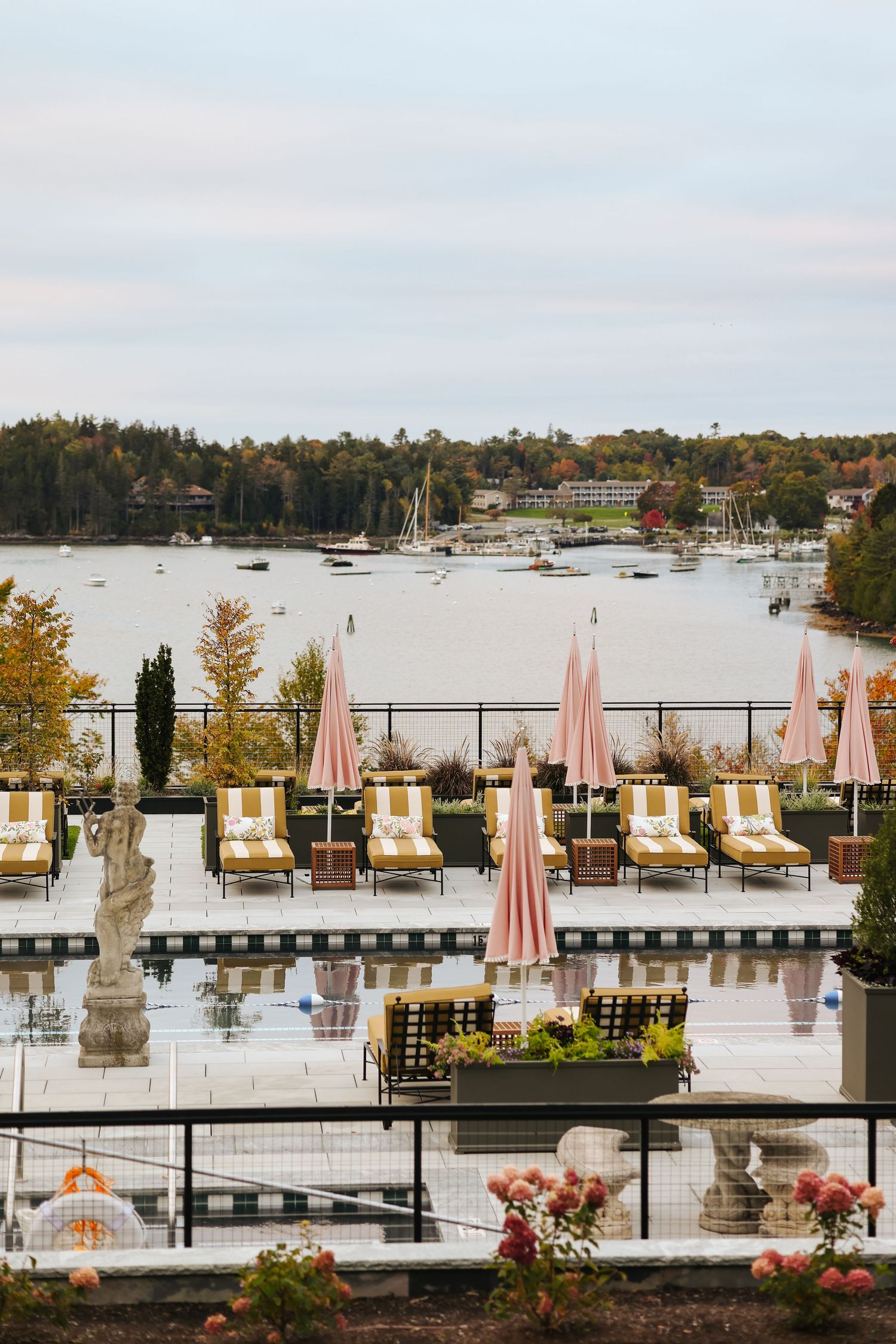 Boutique hotel pool in Maine with yellow lounge chairs and pink umbrellas, hospitality photography highlighting outdoor relaxation space