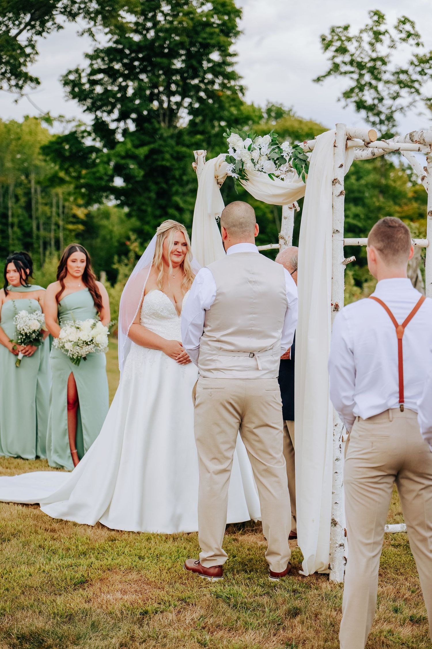 Wedding party in mint green dresses and khaki suits posed outdoors.